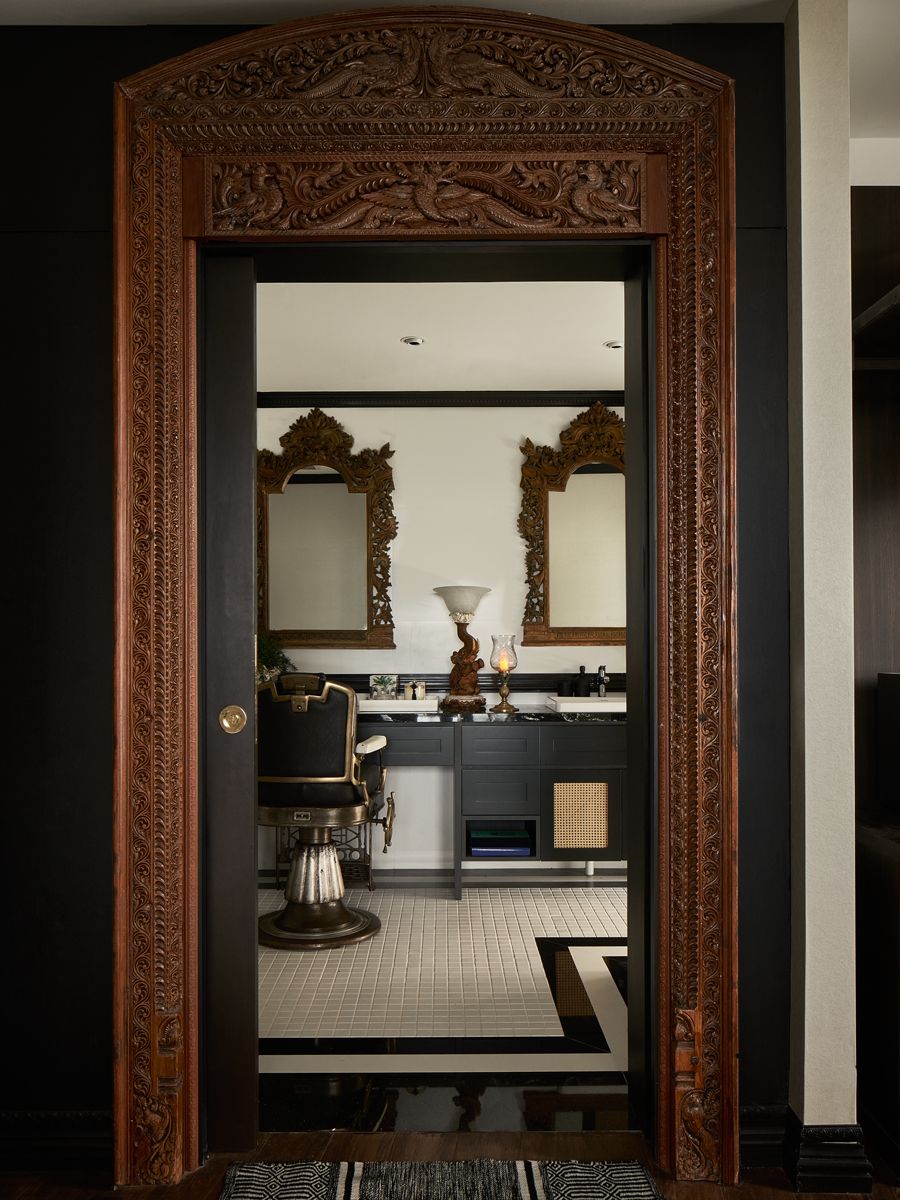 A barber chair creates an intriguing accent in the master bathroom, which is framed by an antique wooden door casing; another view of the bathroom