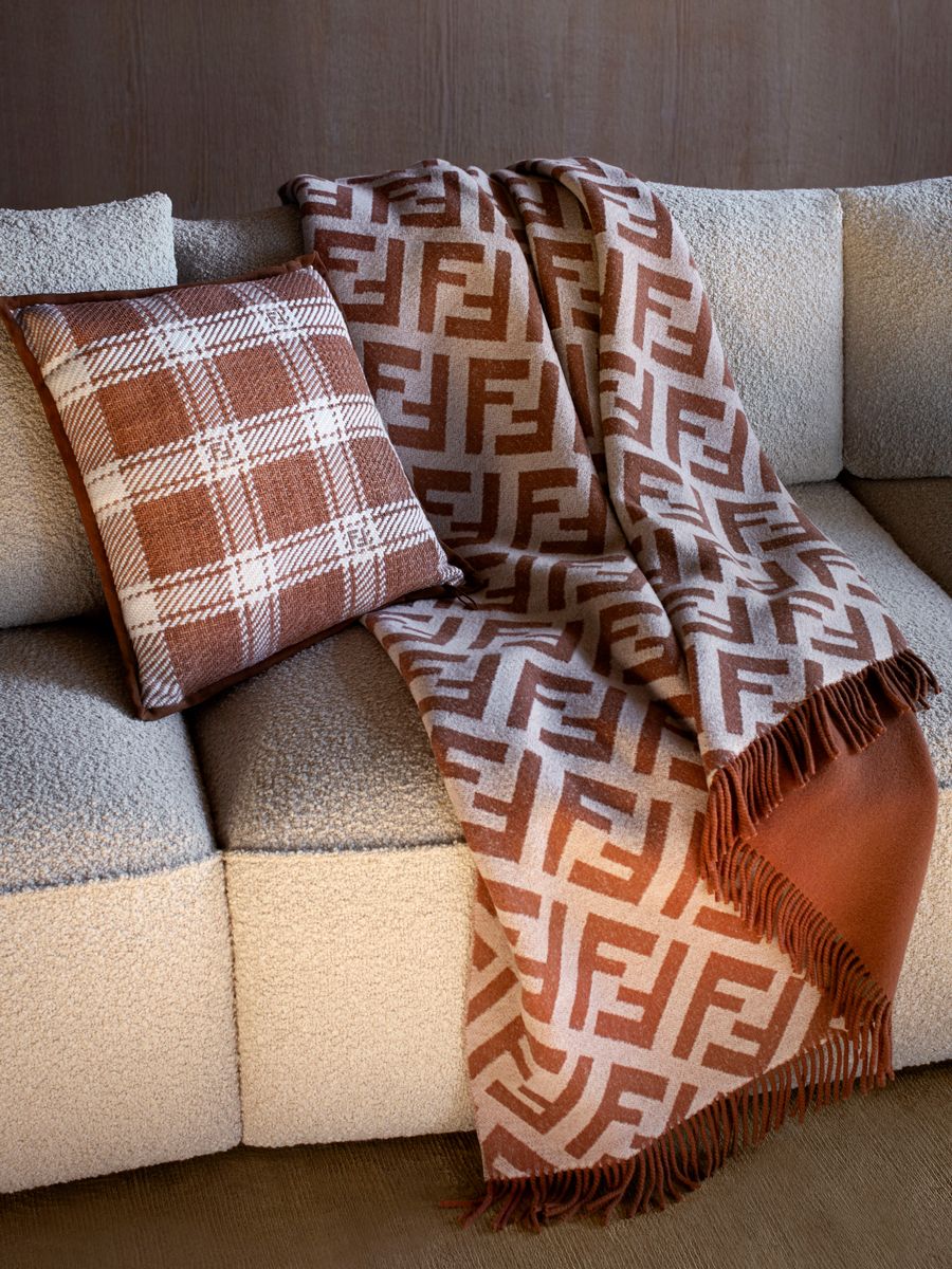 Fendi Casa's accessories include a throw blanket with the signature “FF” motif and a pillow