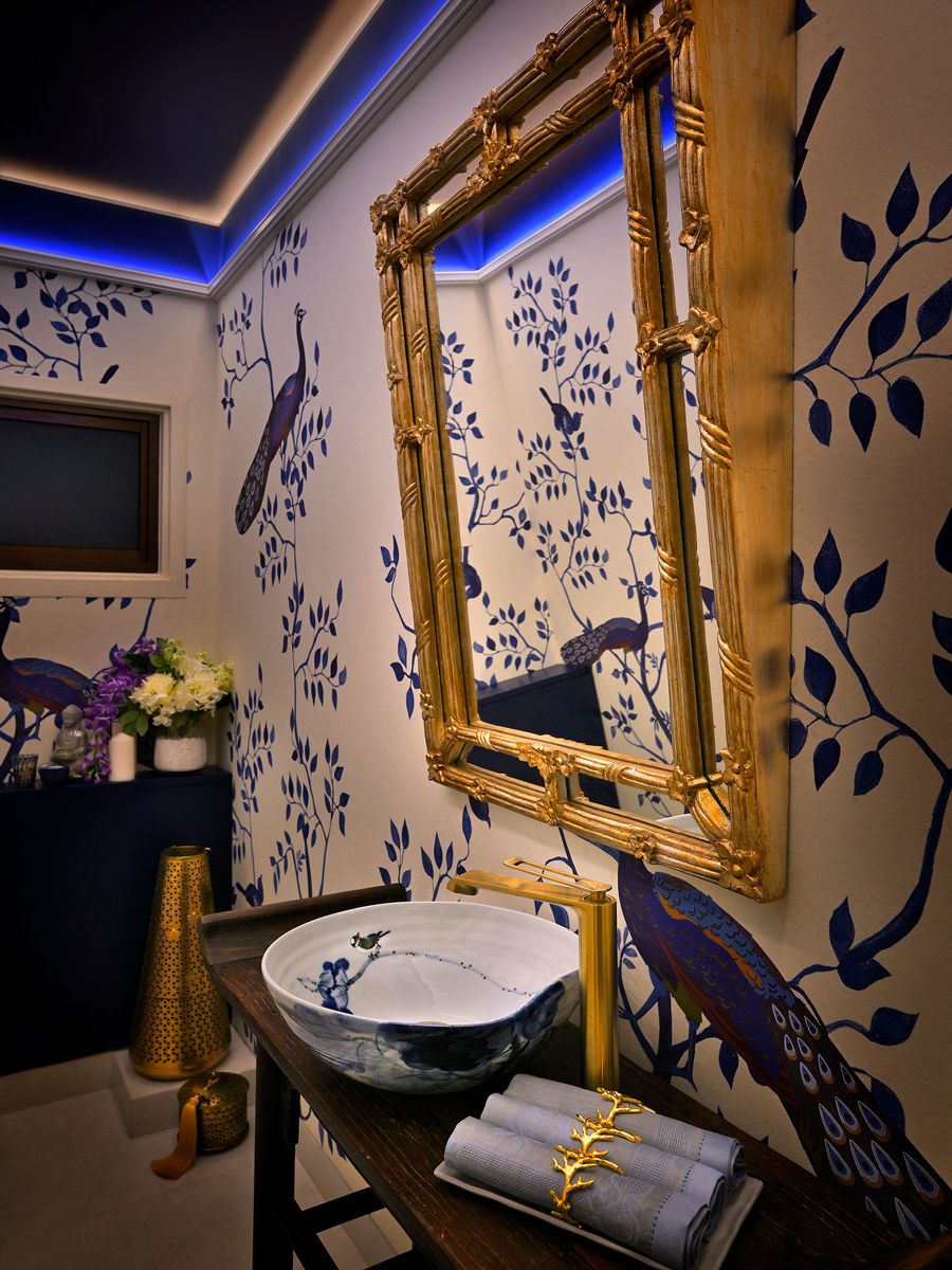 The powder room featuring a striking peacock motif wallpaper and gold accents