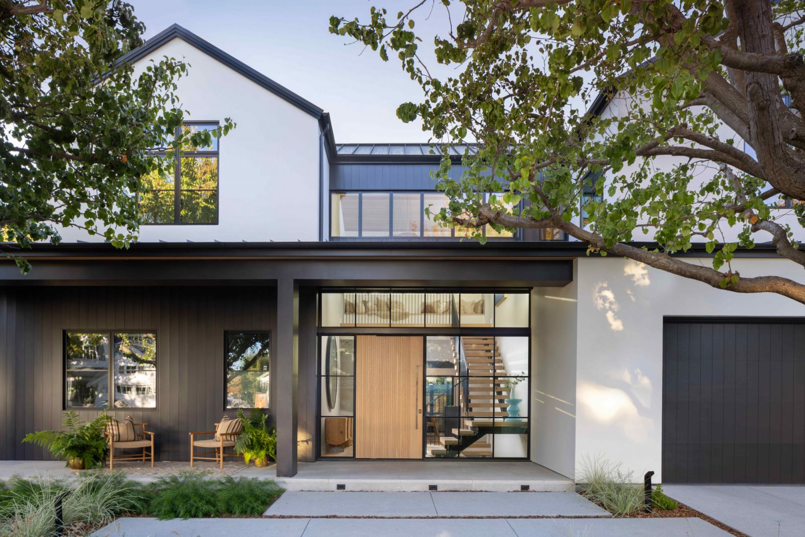 The stucco and dark black vertical sizing exterior, anchored by a ribbed wooden front door