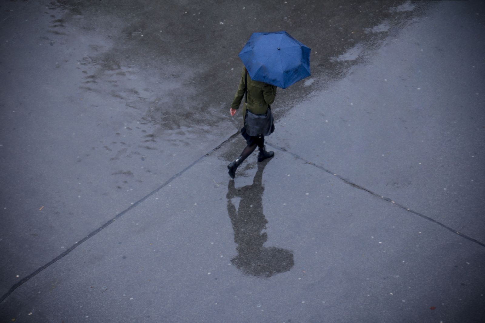 Person walking on street on rainy day with open umbrella.