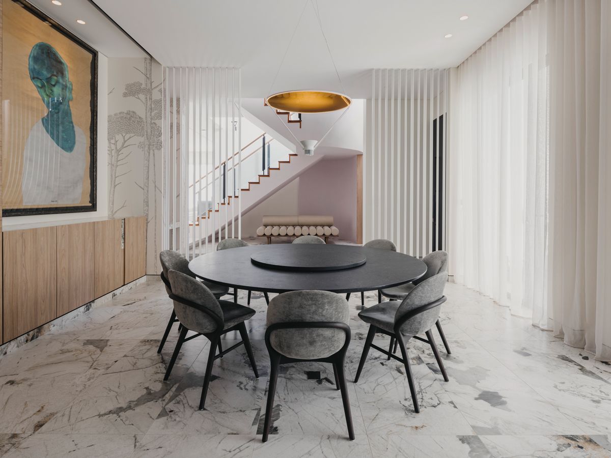 A set of Porada Lip dining chairs encircles the Lema dining table, which comes with a lazy Susan to suit the family’s communal dining habits. This space also features a concealed door leading to a wine cellar (Photo: Marc Tan / Studio Periphery)
