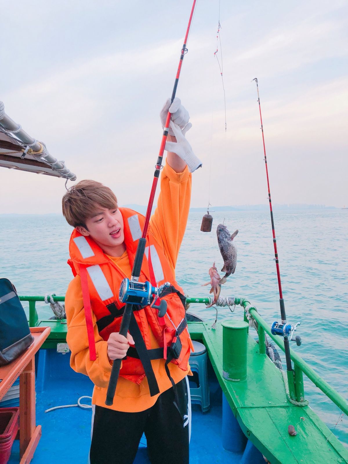 Jin with a fish he caught (image courtesy of X / @bts_bighit)