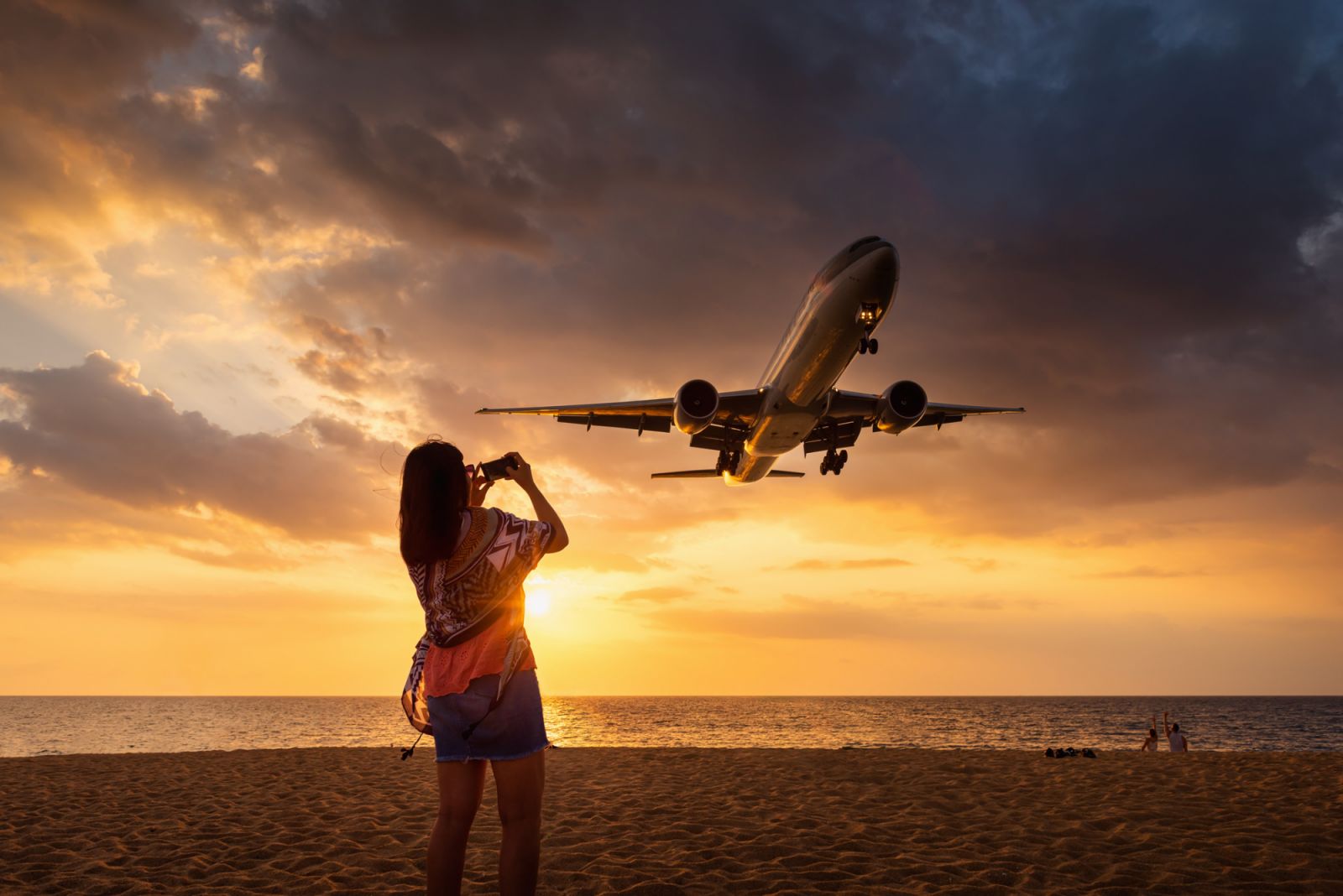 Portrait of Attractive Woman on The Beach While Enjoyment Photographing The Aircraft Landing Over Land at Phuket International Airport.