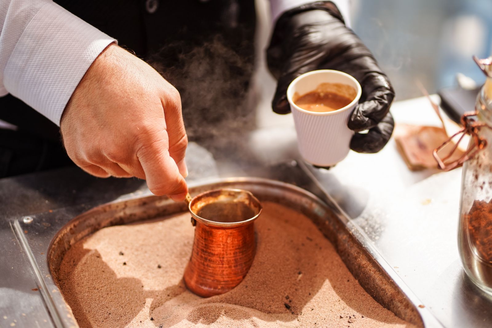 Male hand preparing Turkish coffee in burning sand at Souq Waqif, Doha, Qatar