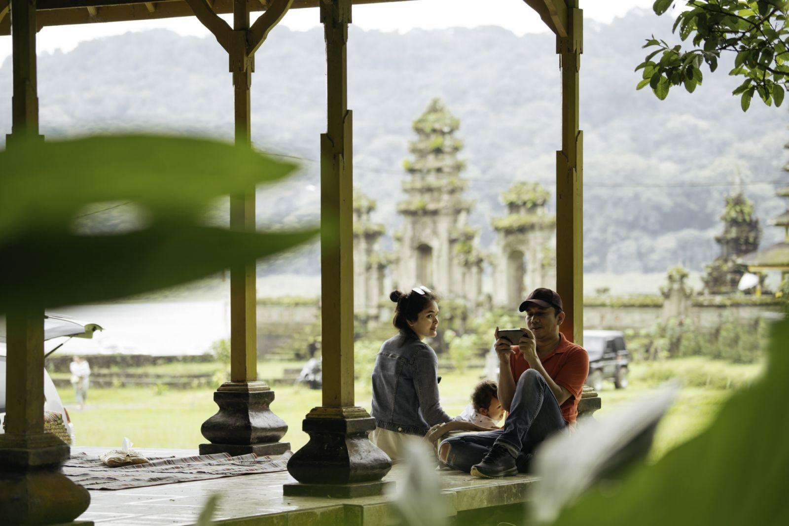 Asia, Indonesia, Bali, asian family sitting inside pavillion enjoy the travel, in front of Tamblingan water temple, while sightseeing.