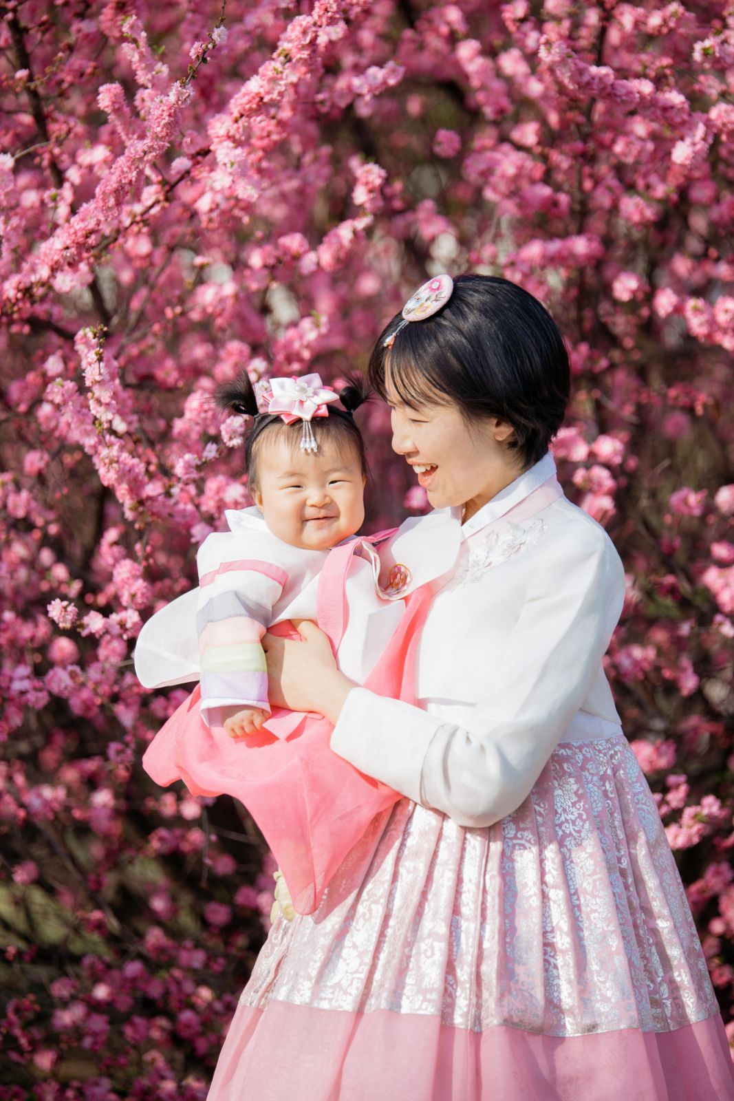 A pretty young mother holding her smiling baby dressed in traditional costume.