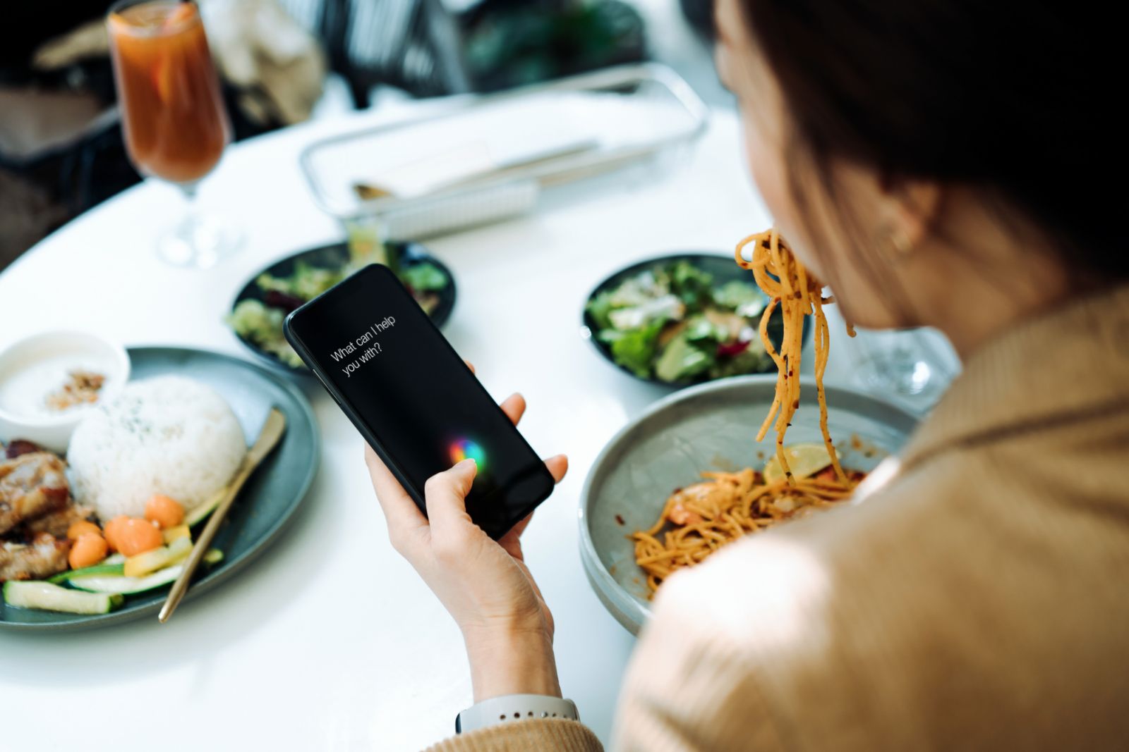 Seorang wanita Asia menggunakan aplikasi masakan berbantukan AI pada telefon pintarnya semasa sedang makan (Foto: Getty Images)