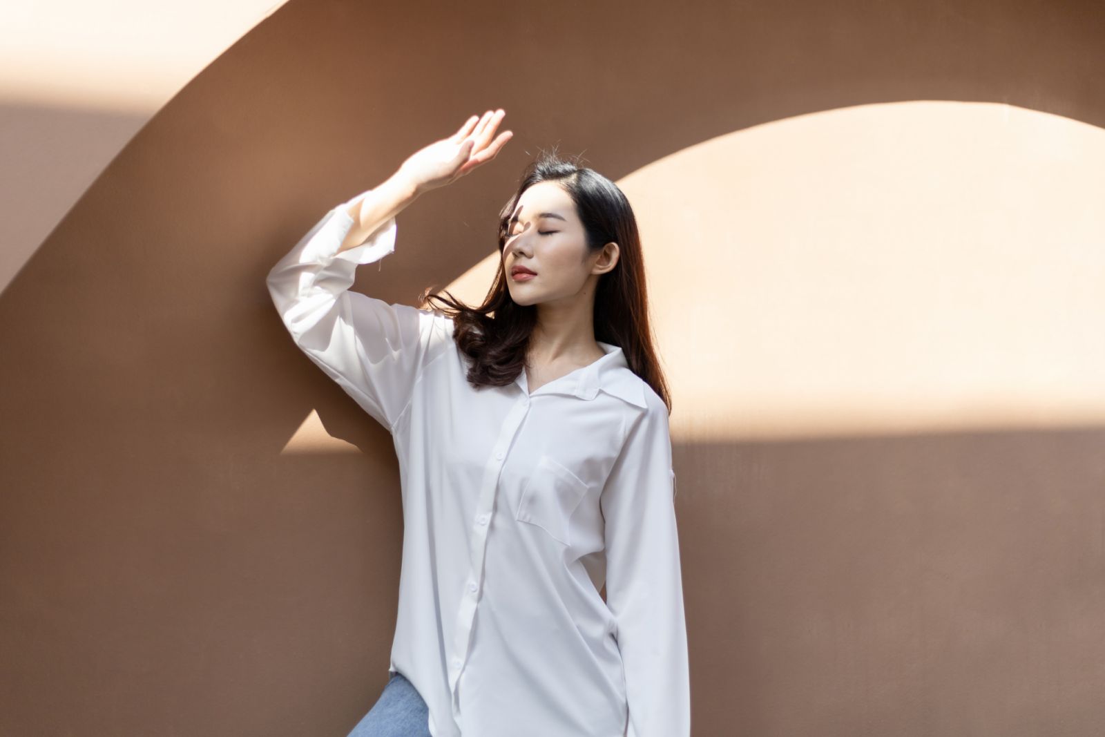 Portrait of a beautiful Asian woman with healthy skin. She uses a sun protection hand that hits her face to protect against UV that has caused her face to dull.