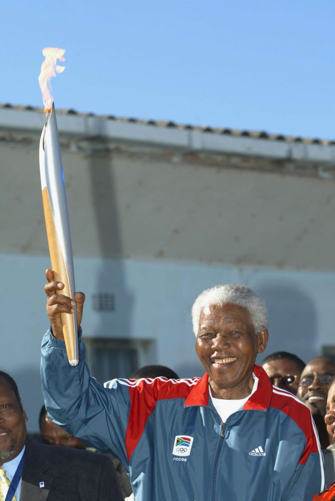 CAPE TOWN, SOUTH AFRICA - JUNE 12:  Nelson Mandela holds the Olympic Flame on Robben Island during Day 9 of the ATHENS 2004 Olympic Torch Relay June 12, 2004 in Cape Town, South Africa. The Olympic Flame travels to 34 cities in 27 countries en route to the Athens 2004 Olympic Games.  (Photo by Todd Warshaw/Getty Images)