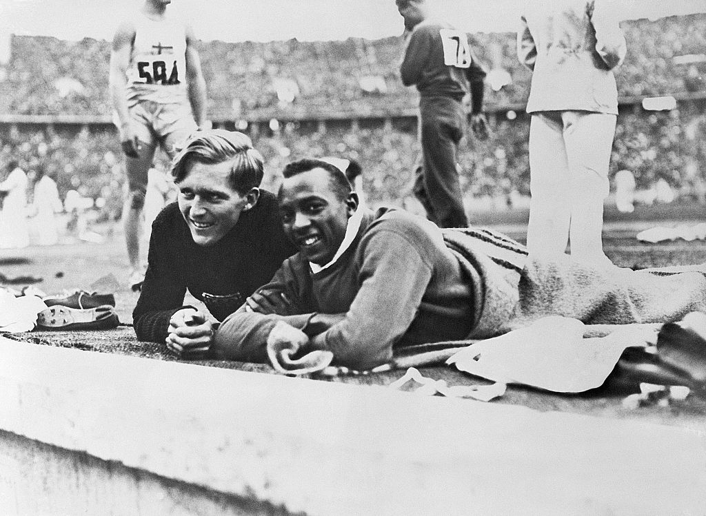 Competitors Luz Long and Jesse Owens seem very amicable watching contestants in the broad jump. Owens, representing the US, took the gold medal, while Long, representing Germany, took silver in the broad jump.