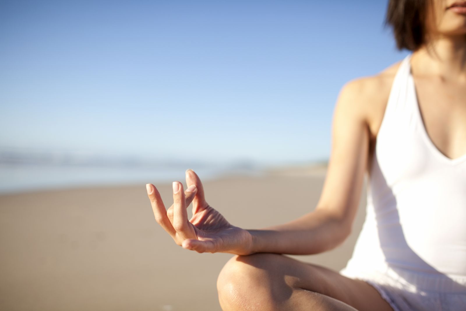 Woman meditating on the beach (Photo via Wander Women Collective)