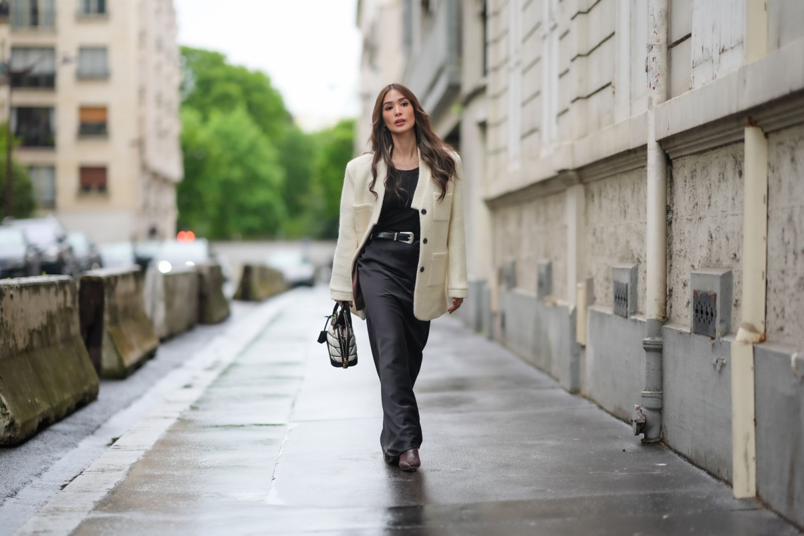 PARIS, FRANCE - APRIL 27: Heart Evangelista wears a white oversize fluffy jacket, a black tank top from YSL Saint-Laurent, a belt from YSL Saint-Laurent, a black and white quilted bag from Louis Vuitton, a black lustrous satin silk shiny long flowing skirt, during a street style fashion photo session, on April 27, 2024 in Paris, France. (Photo by Edward Berthelot/Getty Images)