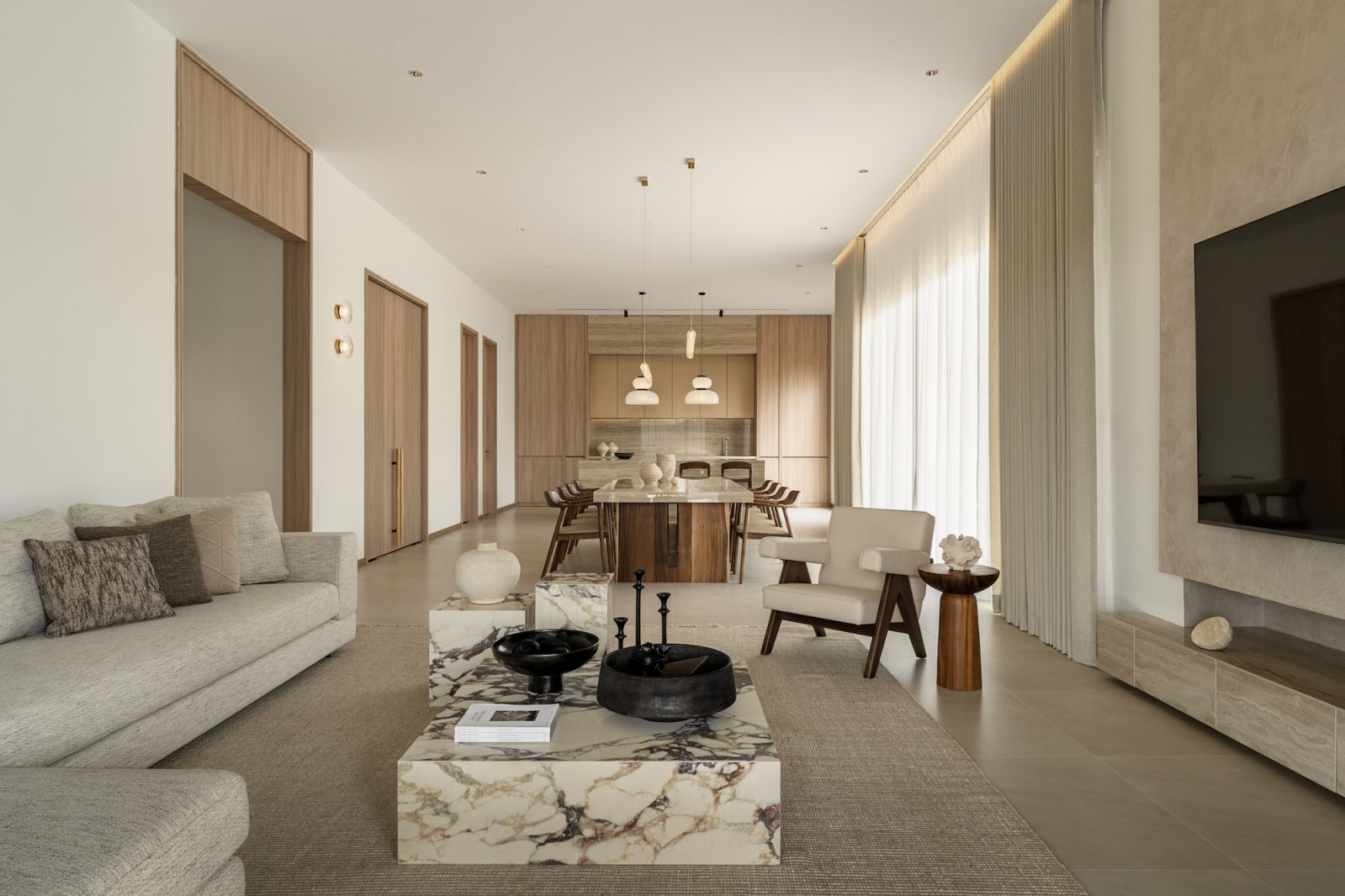 Spacious open-concept living area with neutral tones, marble coffee table, and modern furnishings