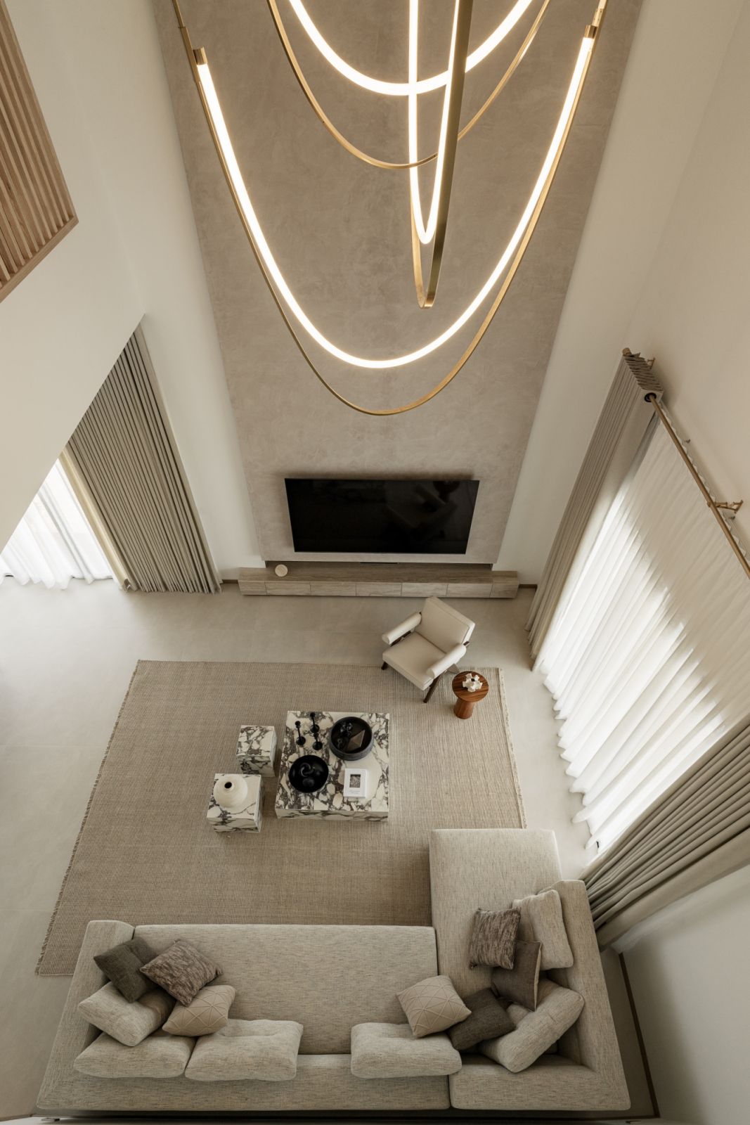 Double-height living room with sculptural light fixture, textured walls, and minimalist decor