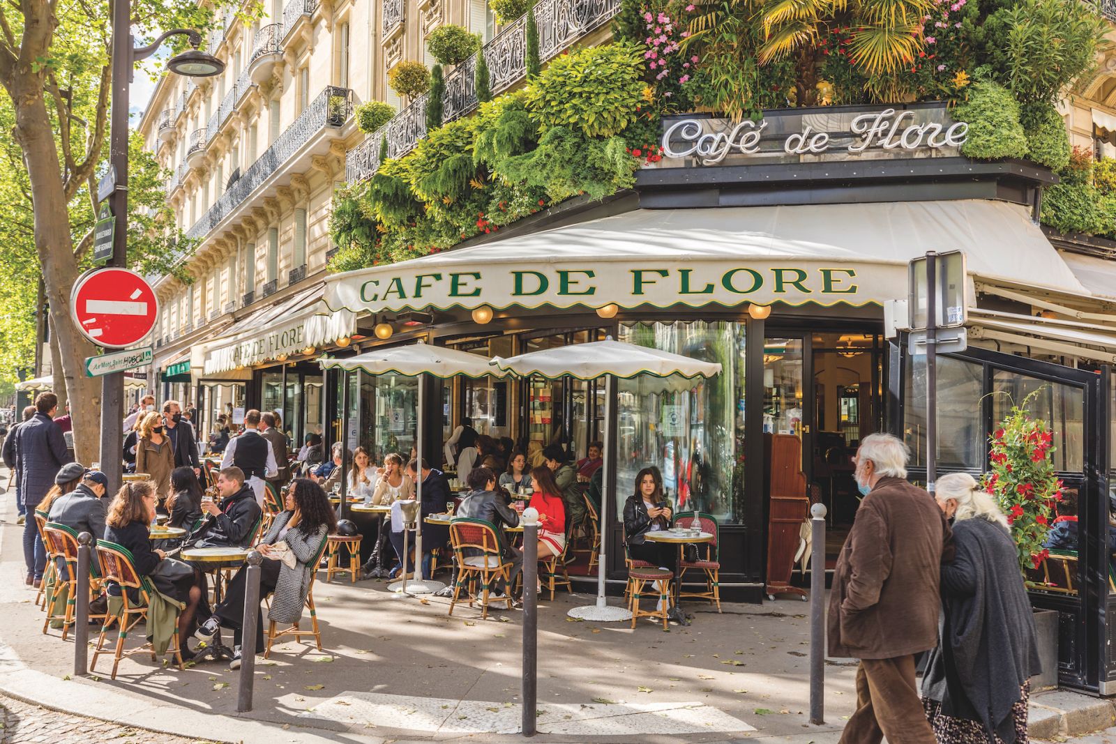 Paris, France - May 19, 2021: Day after lockdown due to covid-19 in a famous Parisian cafe. 2 waiters wear surgical masks