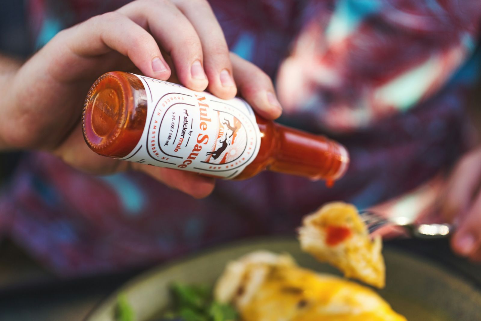 Hot sauce being poured onto a plate of food (Photo: Unsplash)