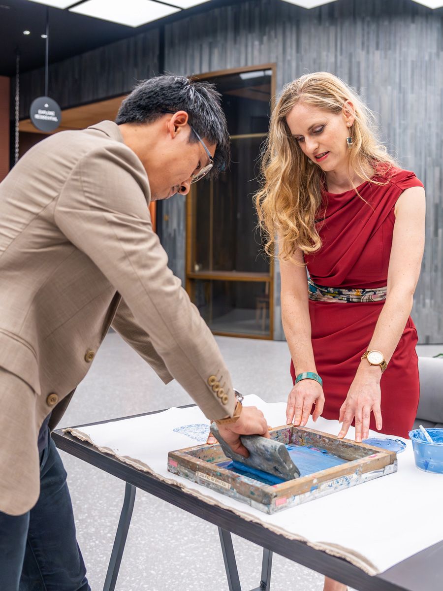 Deborah McKellar observes as Zeeson Teoh tries his hand at silkscreen printing