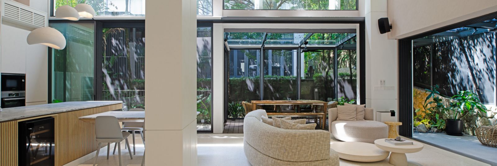 An elegant modern living area with seamless indoor-outdoor integration, featuring comfortable seating, lush greenery, and abundant natural light