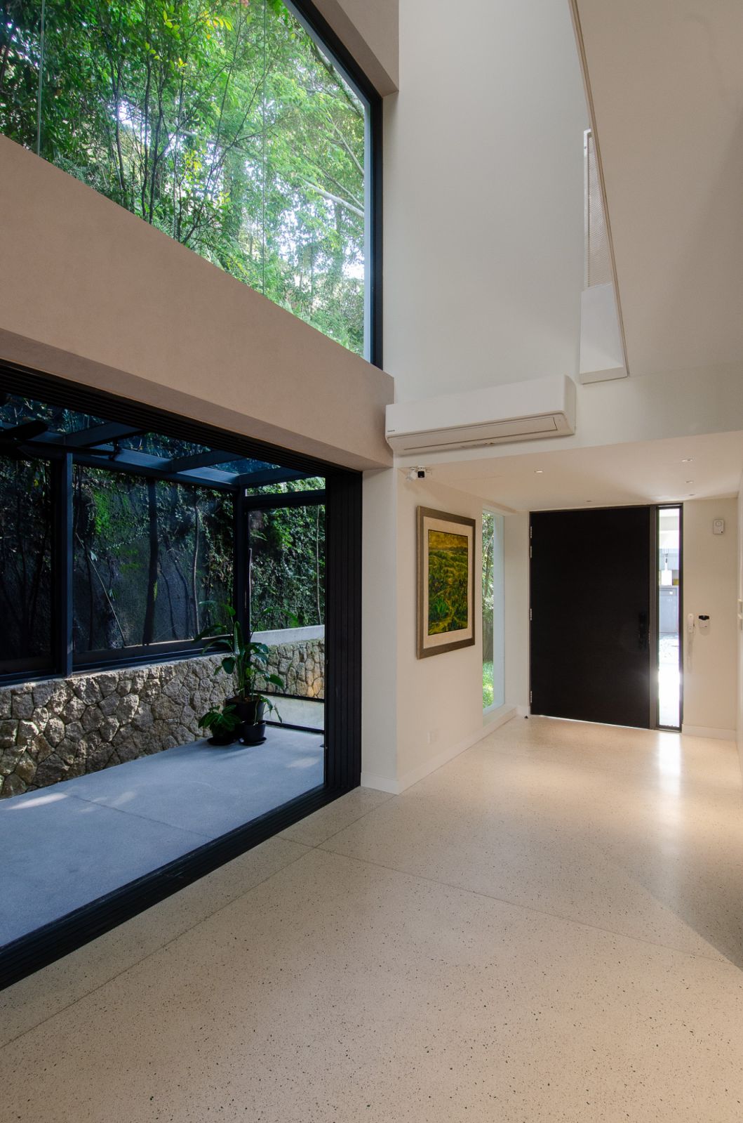 Elegant modern living area with seamless indoor-outdoor integration, featuring comfortable seating, lush greenery, and abundant natural light
