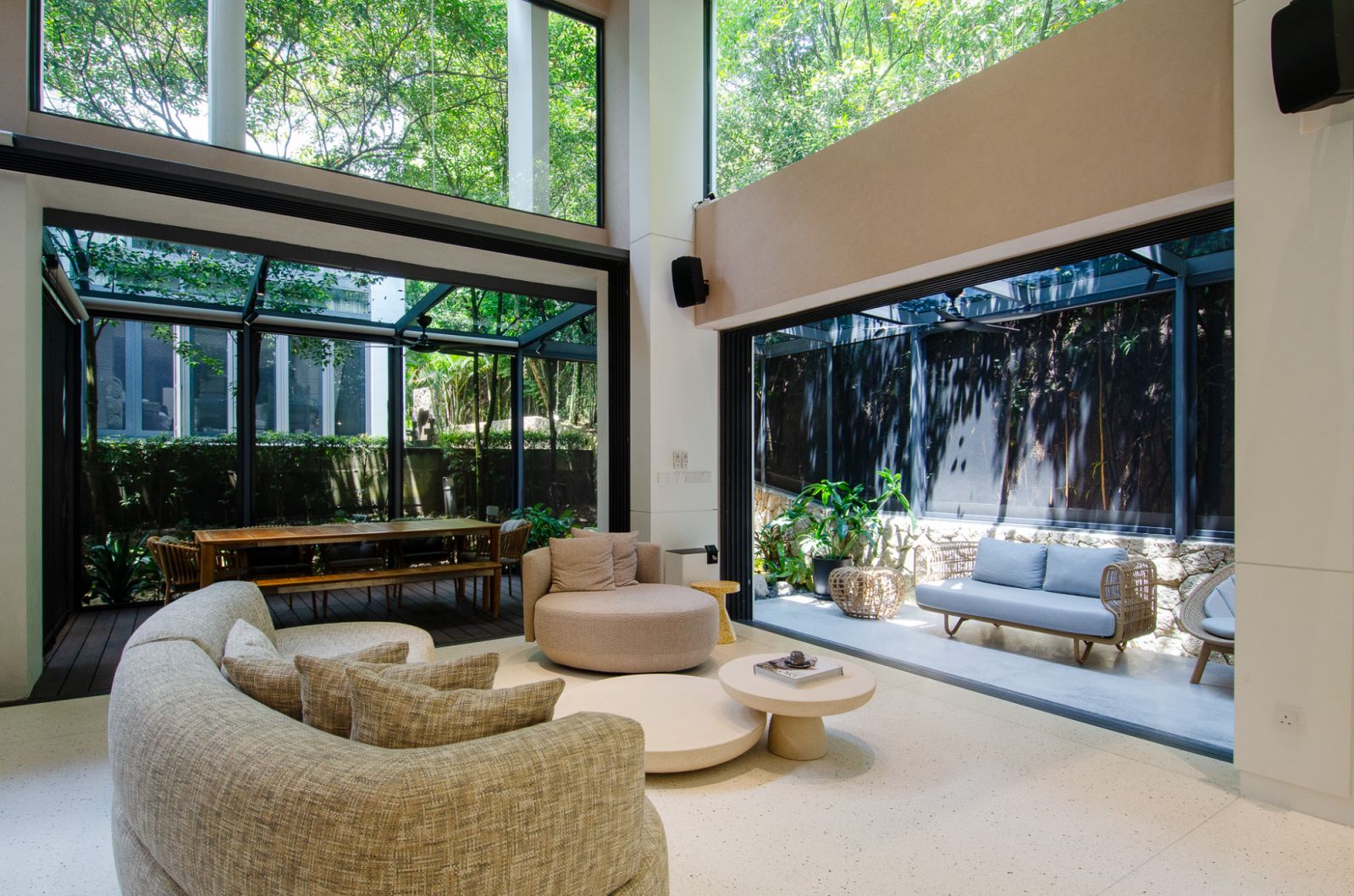 Elegant modern living area with seamless indoor-outdoor integration, featuring comfortable seating, lush greenery, and abundant natural light