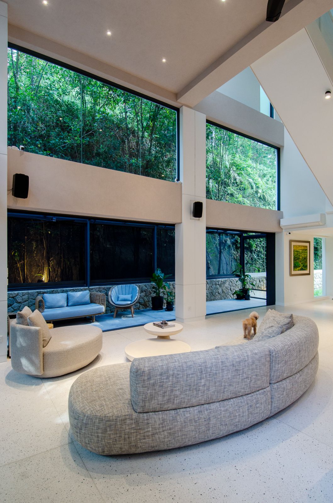 Elegant modern living area with seamless indoor-outdoor integration, featuring comfortable seating, lush greenery, and abundant natural light