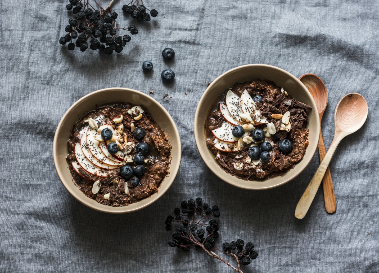 Chocolate oatmeal with apples and blueberries - healthy vegetarian breakfast on a grey background, top view. Flat lay, copy space