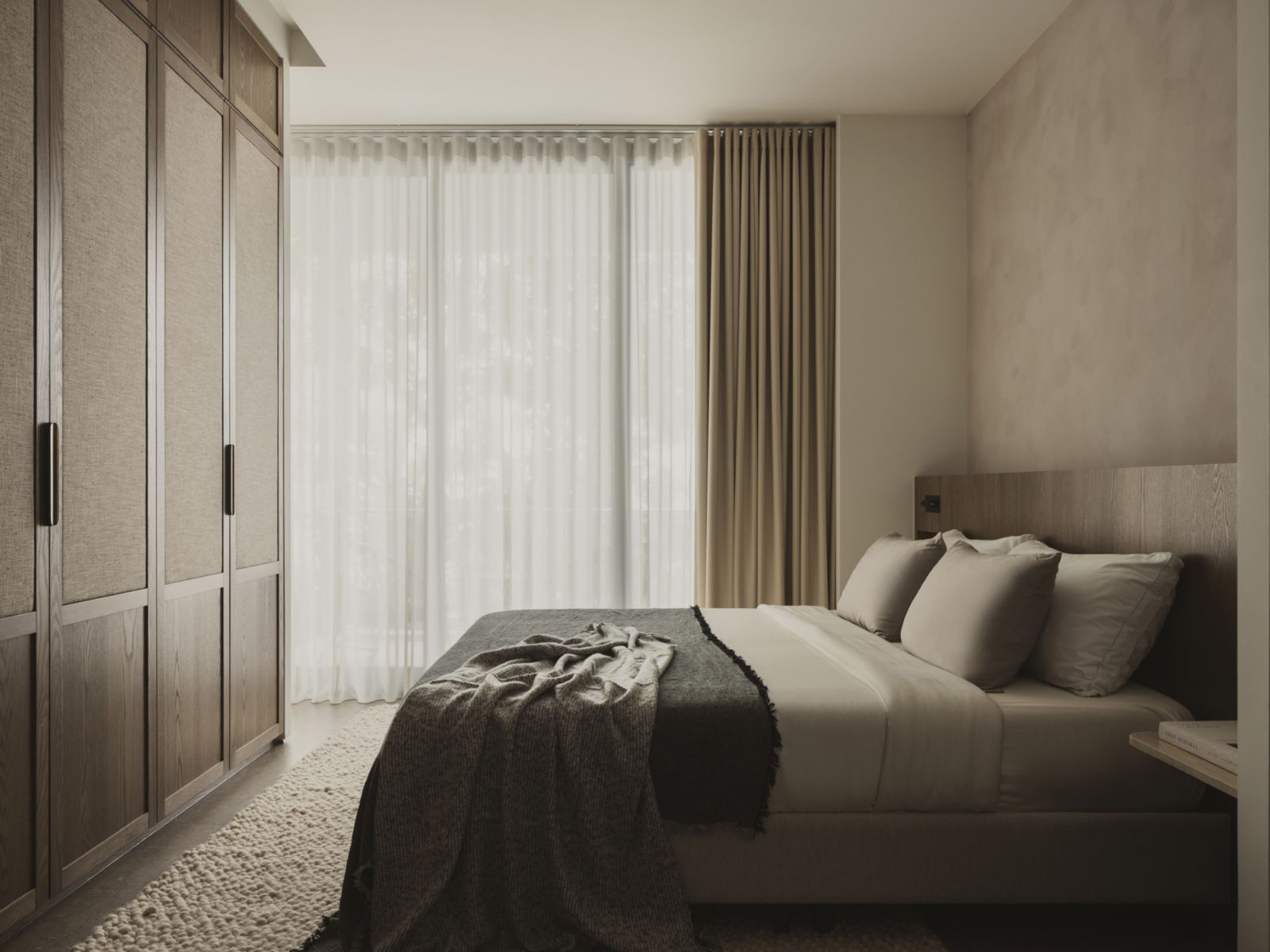 The master bedroom incorporates a row of timber-and-linen wardrobes in front of the bed
