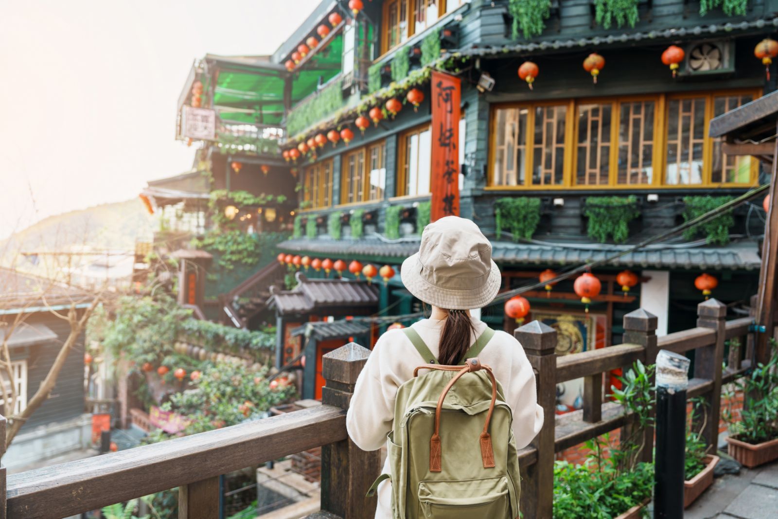 woman traveler visiting in Taiwan, Tourist with hat and backpack sightseeing in Jiufen Old Street village with Tea House background. landmark and popular attractions near Taipei city. Travel concept