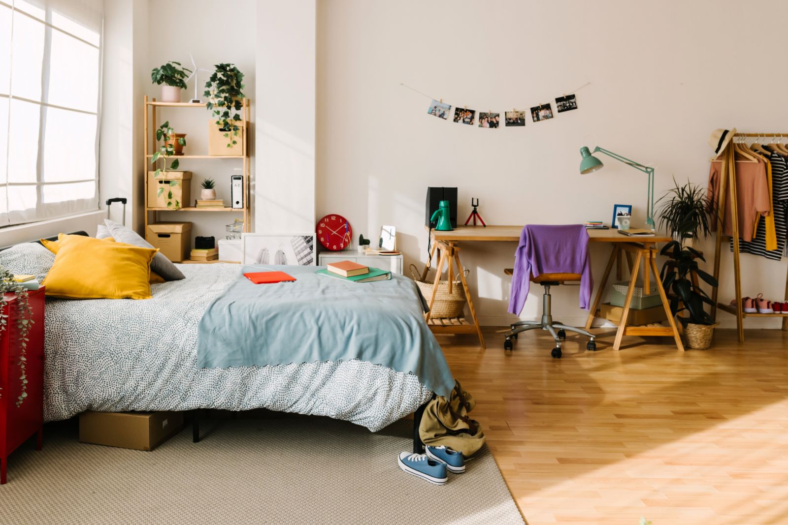 Cozy interior gen z teenager room with bed, workplace, digital devices, plants, photos and some clothes. Home interior room.