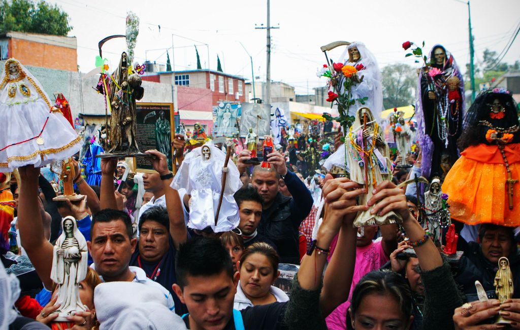 A group of devotees hold the status of Santa Muerte, a Mexican folk saint of death, as they parade at the capital of Mexico (Photo: Getty Images)