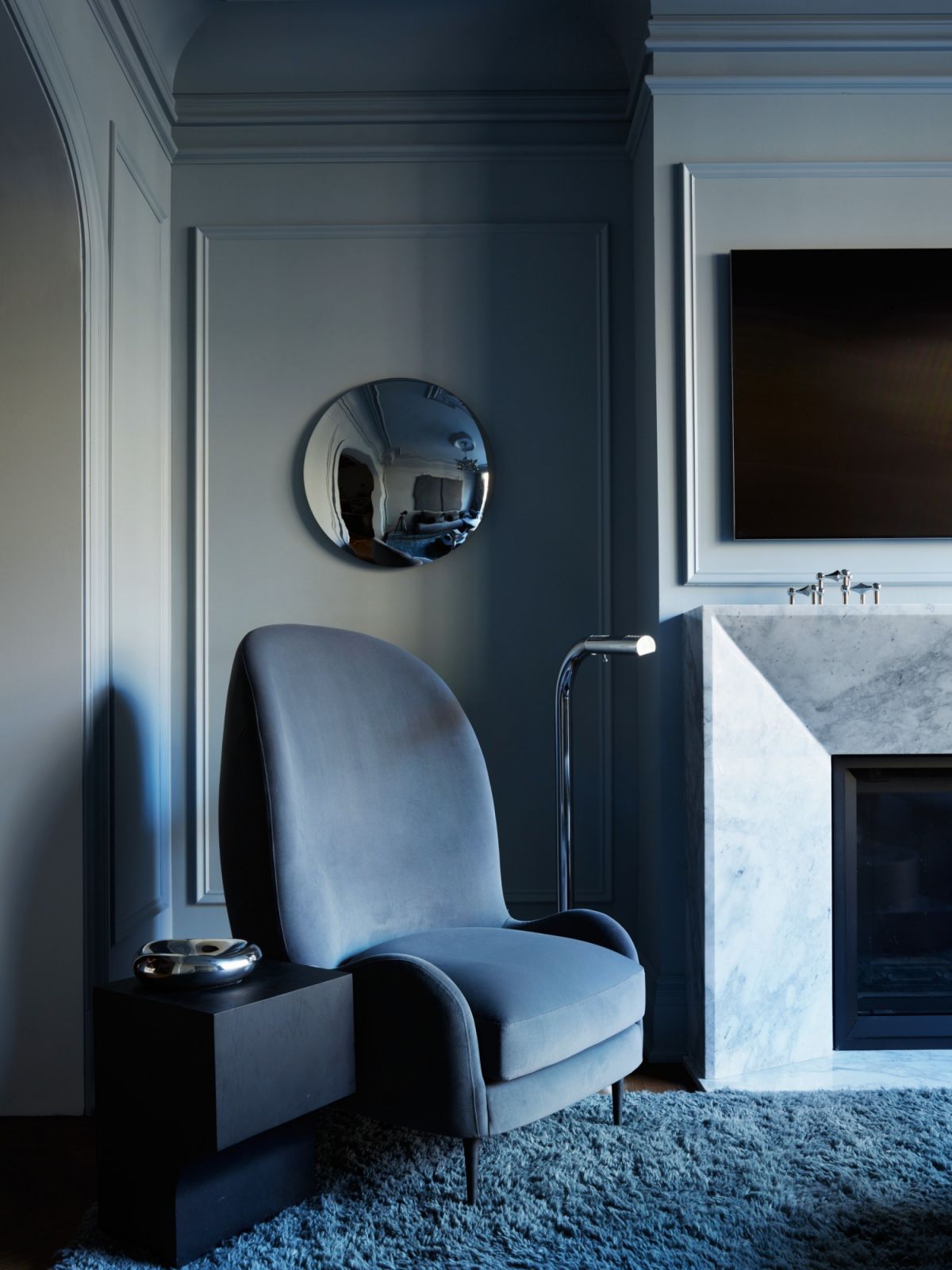 Furnishings with circular accents juxtapose the angular marble mantel