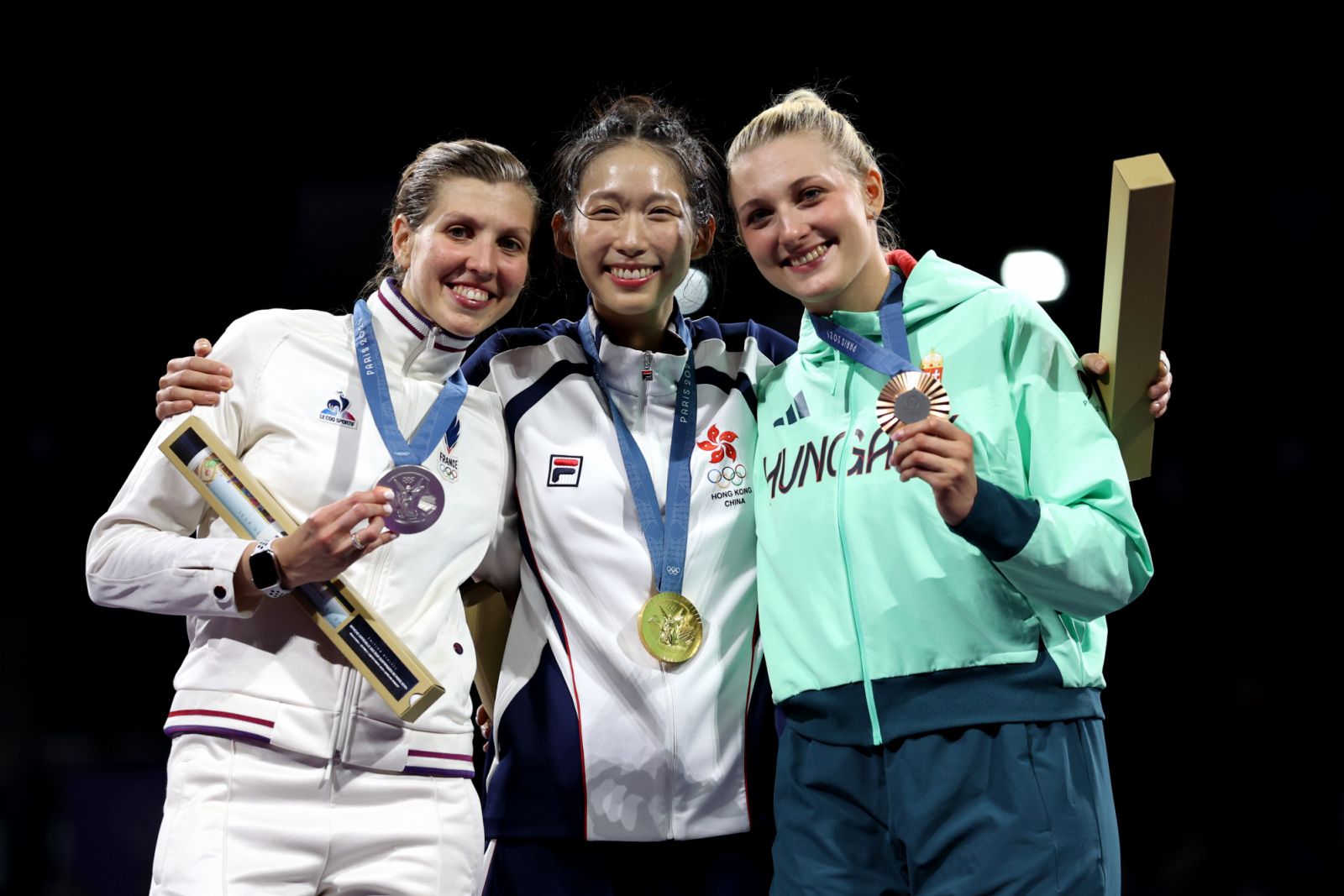 PARIS, FRANCE - JULY 27: Gold medalist Man Wai Vivian Kong of Team Hong Kong (C), Silver medalist Auriane Mallo Breton of Team France (L) and Bronze medalist Eszter Muhari of Team Hungary (R) celebrate on the podium during the Women's Épée Individual meadal ceremony on day one of the Olympic Games Paris 2024 at Grand Palais on July 27, 2024 in Paris, France. (Photo by Patrick Smith/Getty Images)