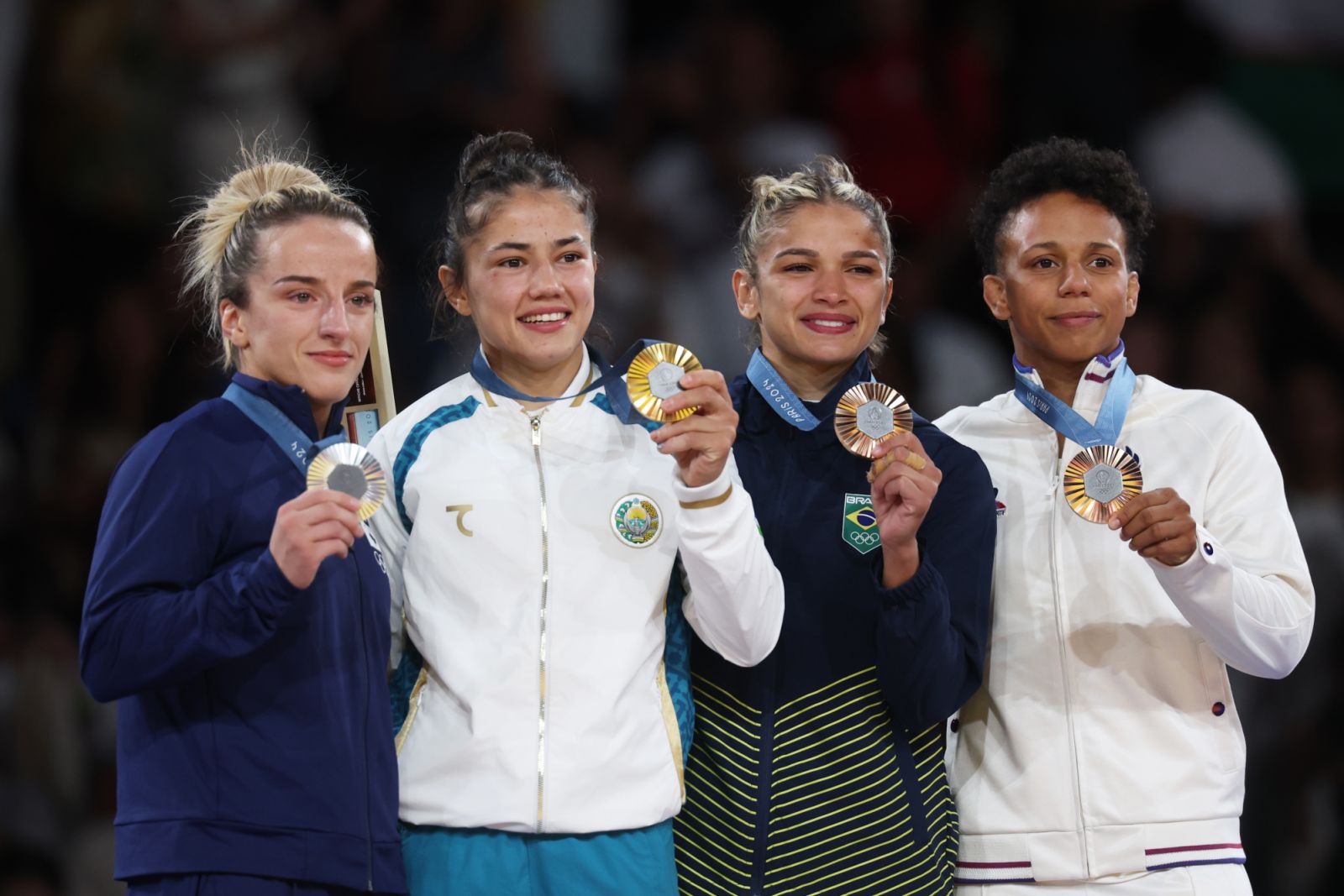 PARIS, FRANCE - JULY 28: Gold medalist Diyora Keldiyorova of Team Uzbekistan (C), Silver medalist Distria Krasniqi of Team Kosovo (L) and Bronze medalists Amandine Buchard of Team France and Larissa Pimenta of Team Brazil (R) pose on the podium during the Women -52 kg tournament on day two of the Olympic Games Paris 2024 at Champs-de-Mars Arena on July 28, 2024 in Paris, France. (Photo by Michael Reaves/Getty Images)