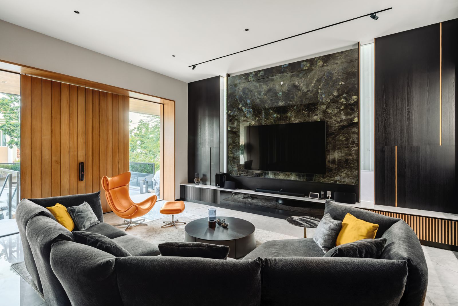 The dark walnut-veneer wall cladding is accented by slabs of bookmatched marble on the floor in the living room