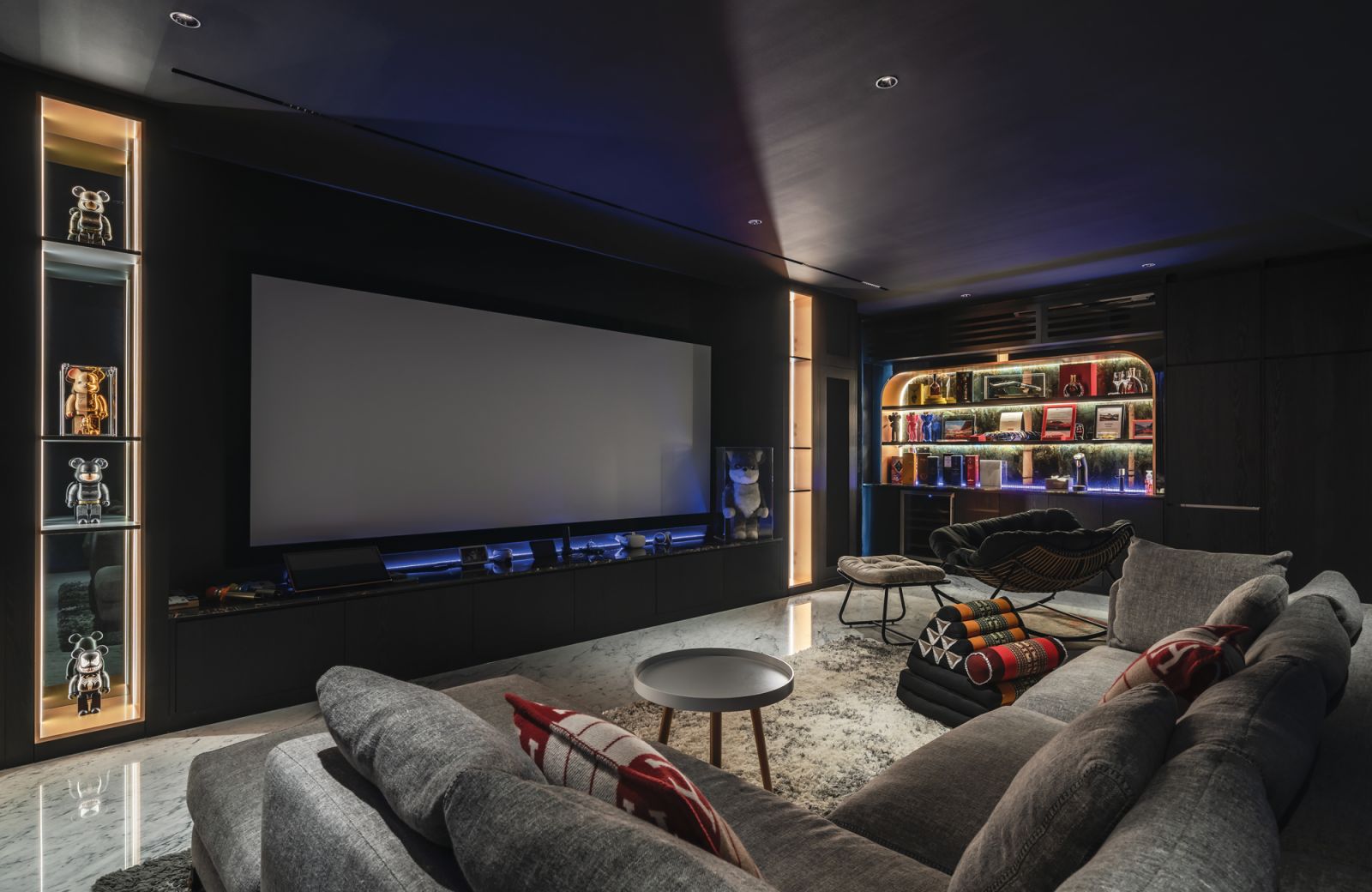 The entertainment room is a dim, cocooning zone punctuated with dashes of colour in the form of liquor bottles, Kaws and Bearbrick figures, and subtle backlighting