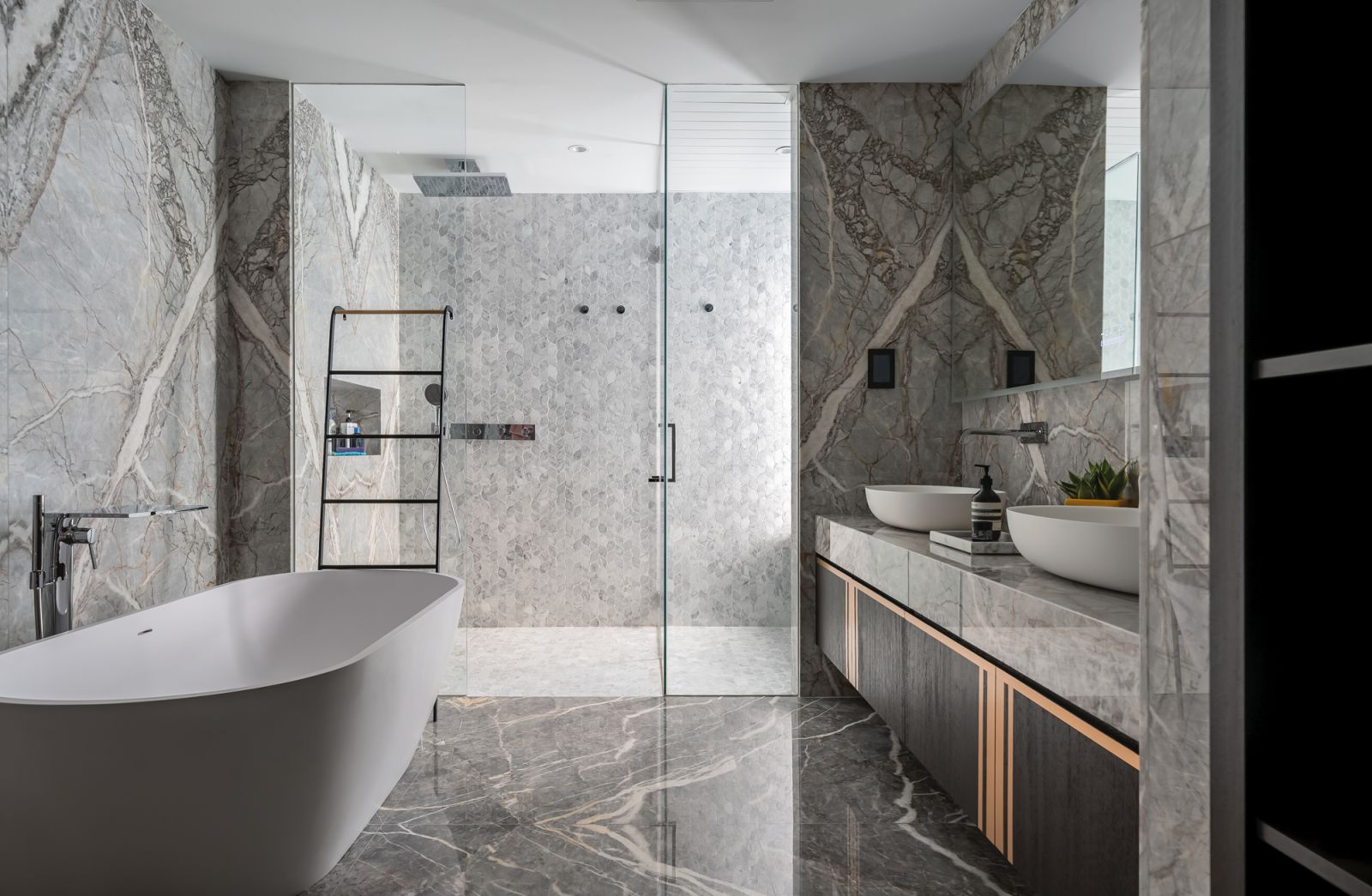 Bookmatched marble slabs on the walls and floor elevate the aesthetic appeal of the master bathroom