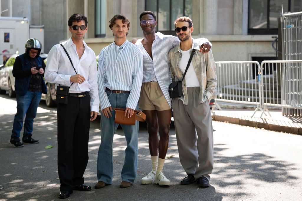 PARIS, FRANCE - JUNE 22: (L-R) Francisco Faria wears light blue and white striped shirt, black trousers, black Hermes bag, black Hermes bag, black sandals, Mergim Shabani wears light blue and white striped shirt, blue jeans, brown Hermes bag, brown boots, Sadiq Adeshina wears light blue and white striped shirt, beige leather shorts, beige socks, cream sandals, Manuel Otgianu wears white top, grey and cream printed jacket, grey trousers, black loafers, black bag, outside Hermes, during the Haute Menswear Spr