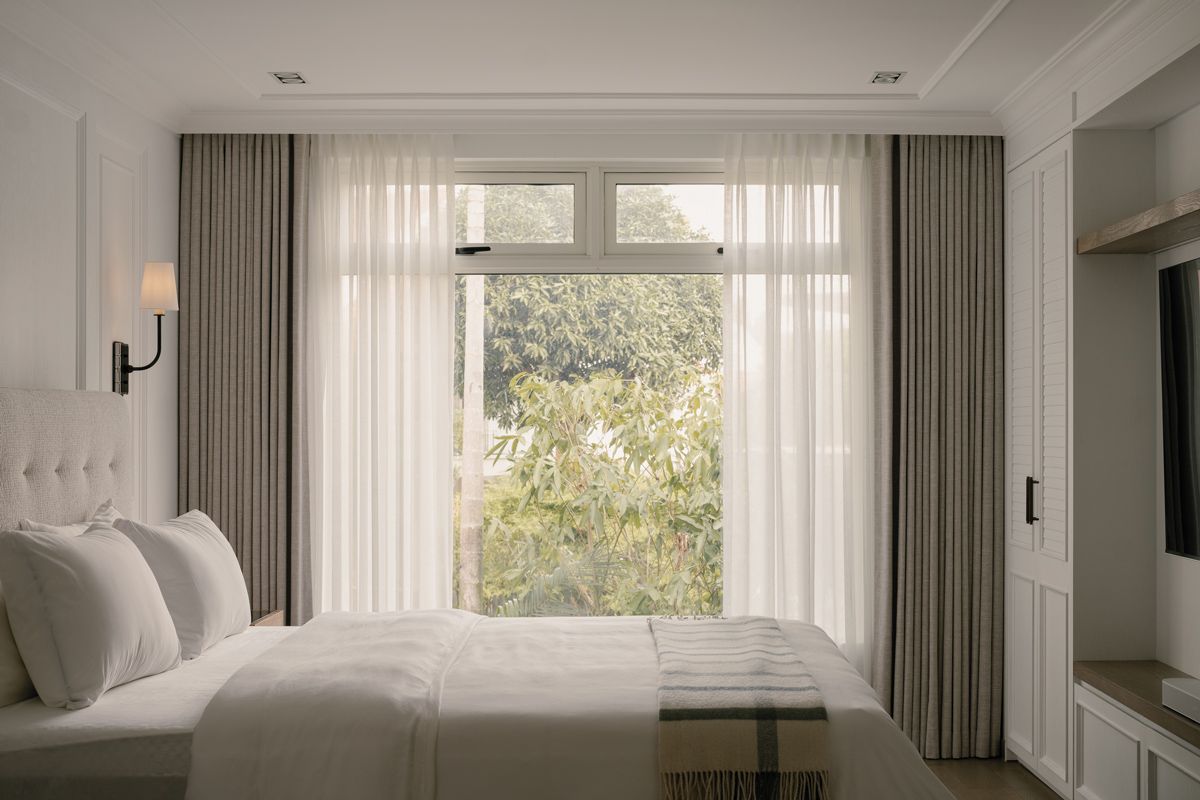 Verdant outdoor greenery forms a living backdrop in the master bedroom