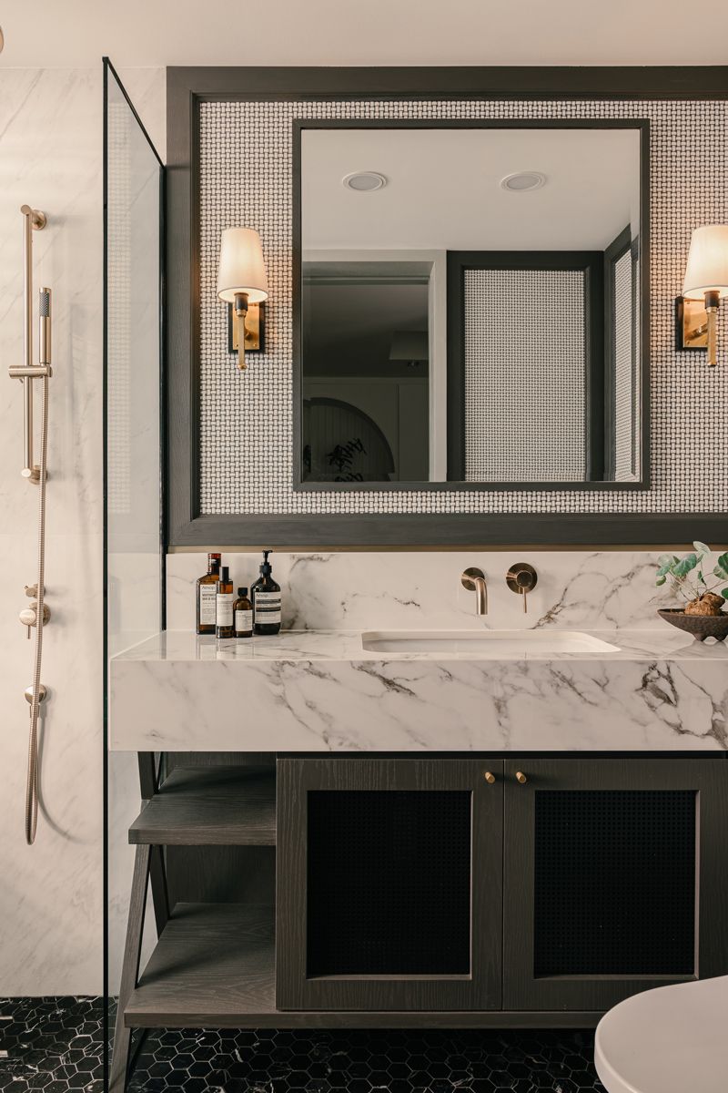 Brass and dark carpentry pair well with marble surfaces in this bathroom