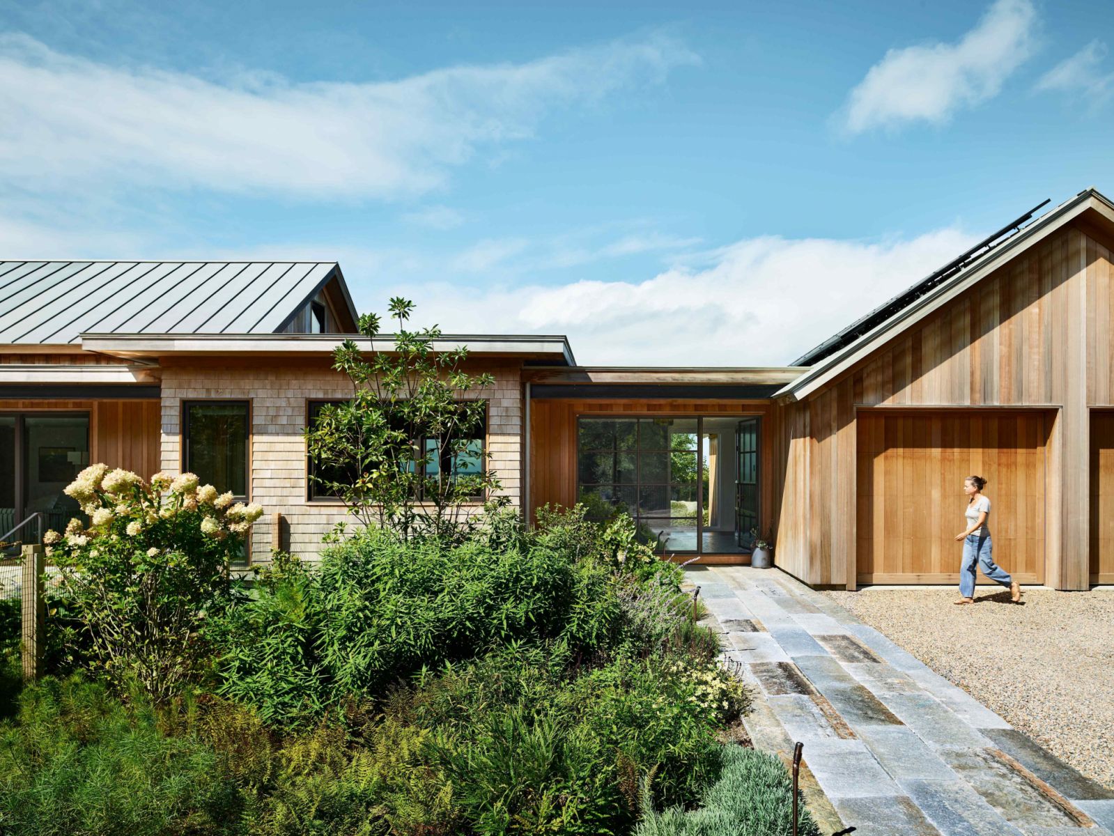 Vertical cedar siding and bronze metal components for the front doors and roof