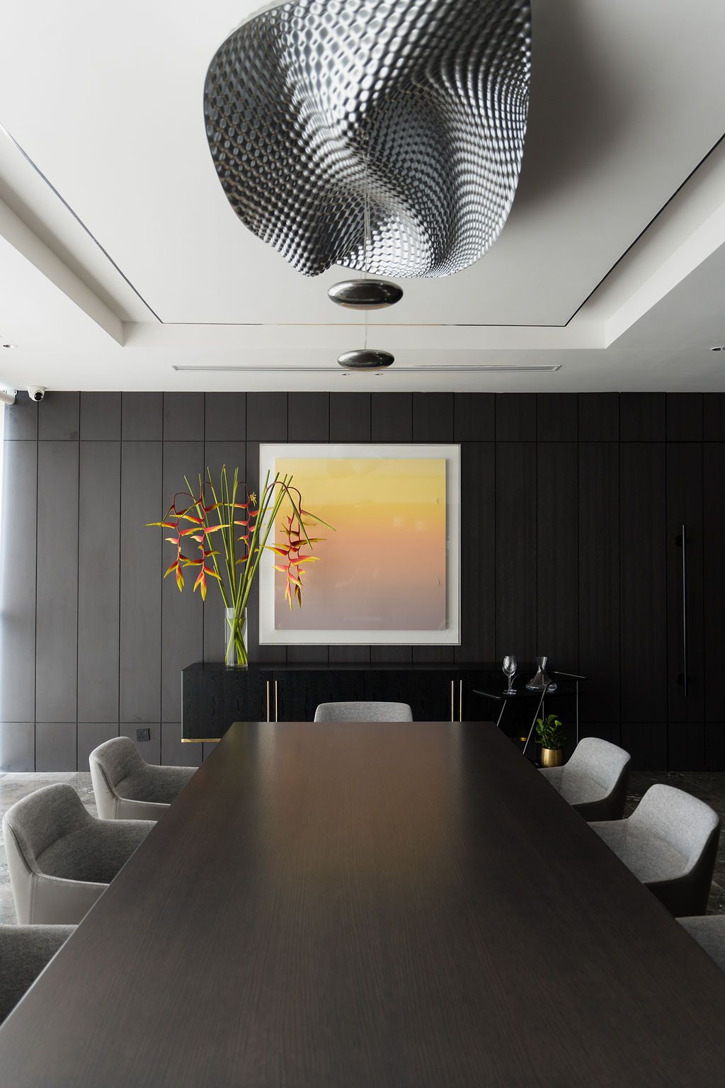 The handsome dining area features artwork and a wavy modern Artemide light by Ross Lovegrove