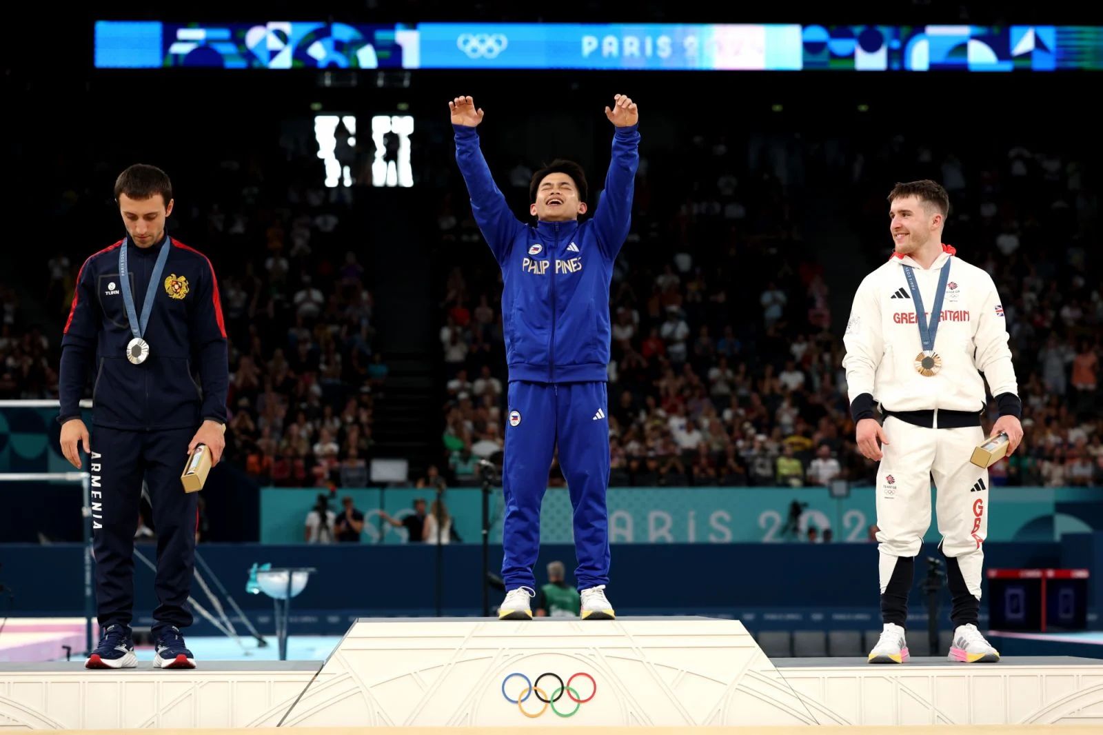 Gold medallist Carlos Yulo (C) from Philippines celebrates on the podium as silver medallist Artur Davtyan (L) from Armenia and bronze medallist Harry Hepworth (R) from Britain look on during the medal ceremony for the artistic gymnastics men's vault event at the Games in Paris (Photo: Getty Images)