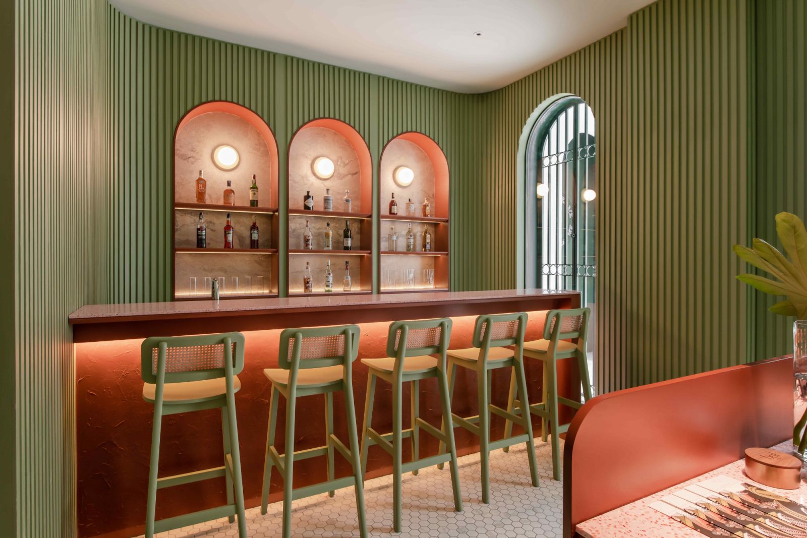 slatted timber walls in sage green, and arched alcoves and rattan-panelled seats in terracotta (Photo: David Yeow)