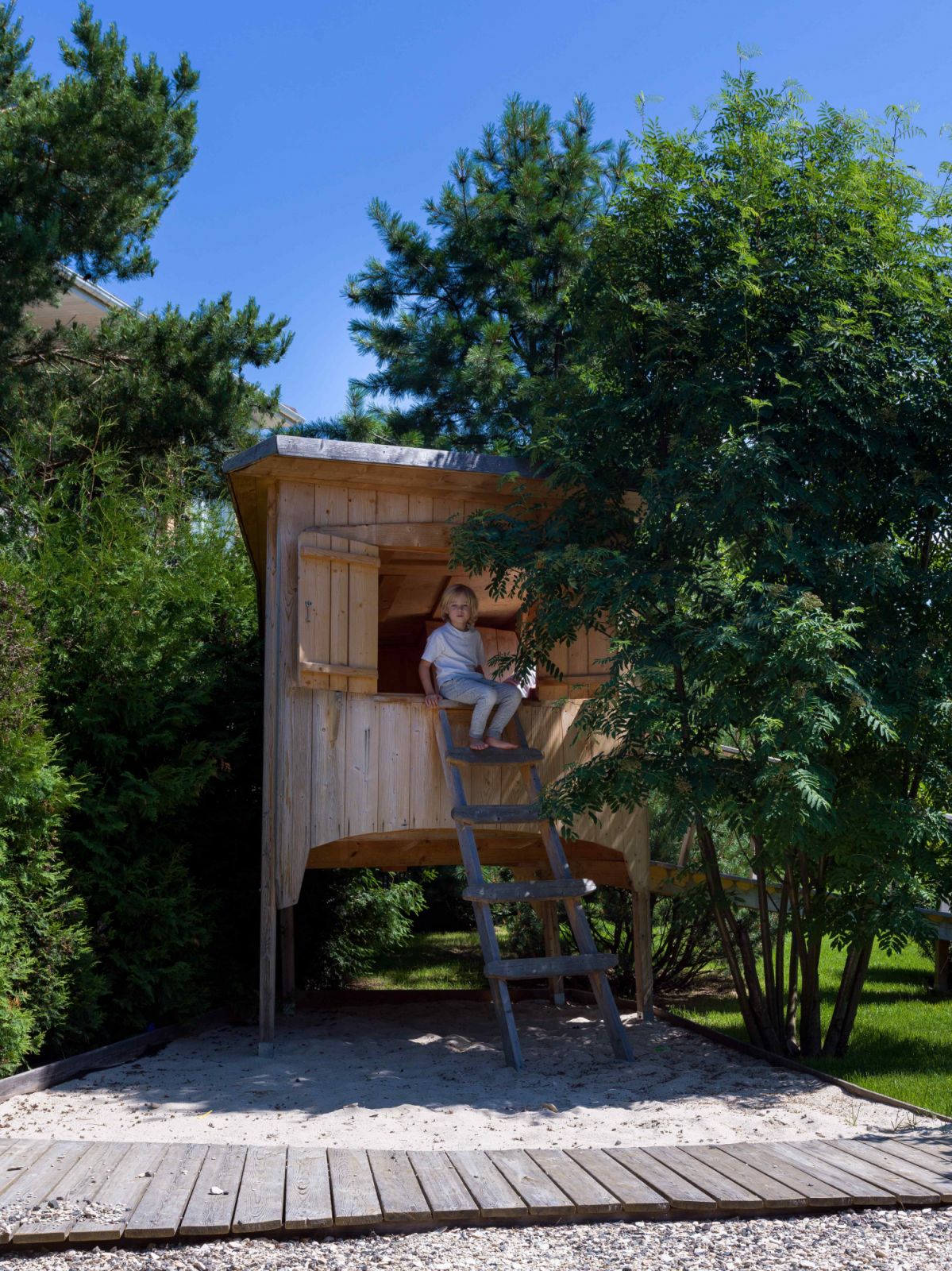 A small wooden house nestled amidst the shady trees for playtime