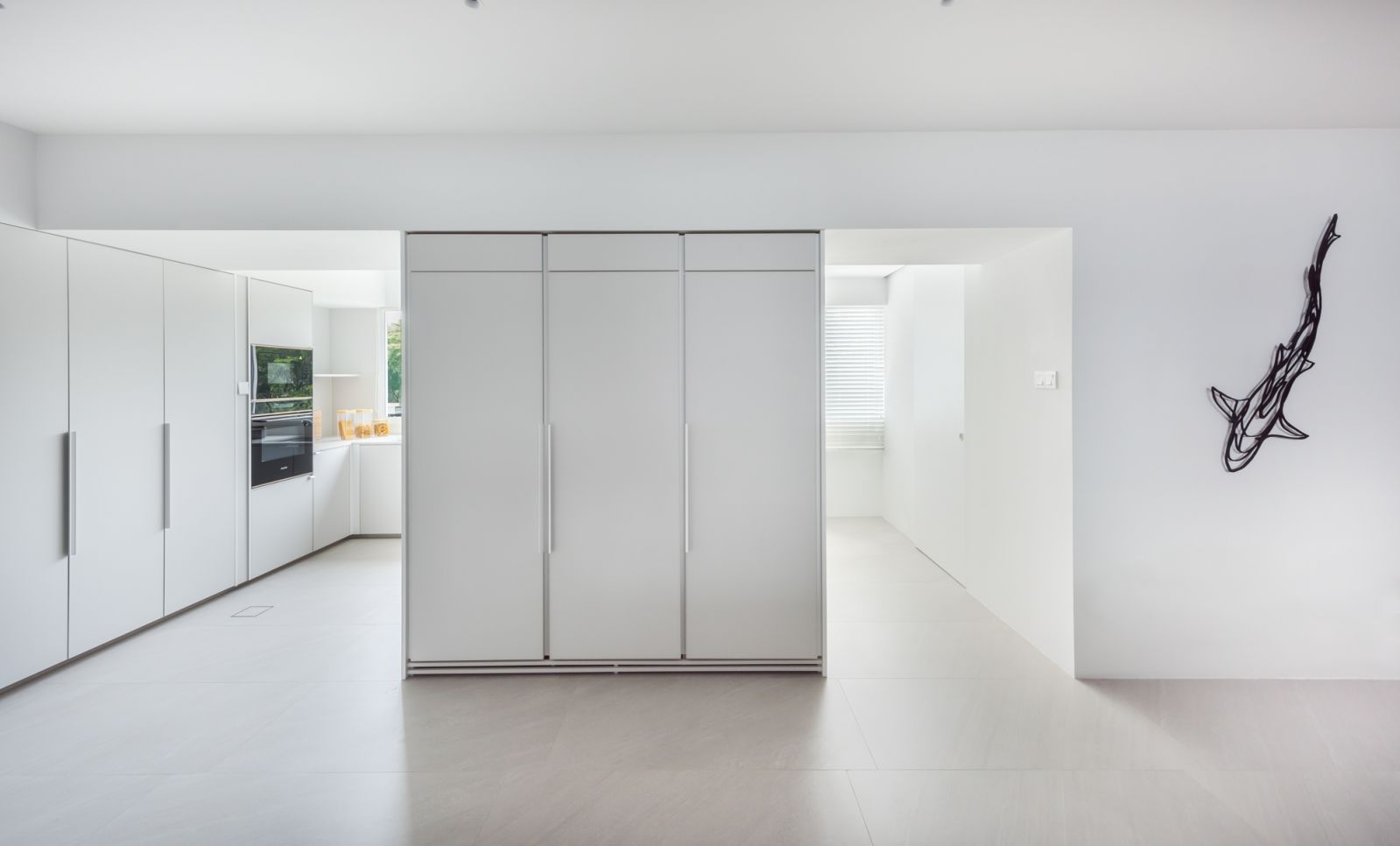 A trio of built-in fridges separates the way to the wet kitchen on the left and powder room on the right