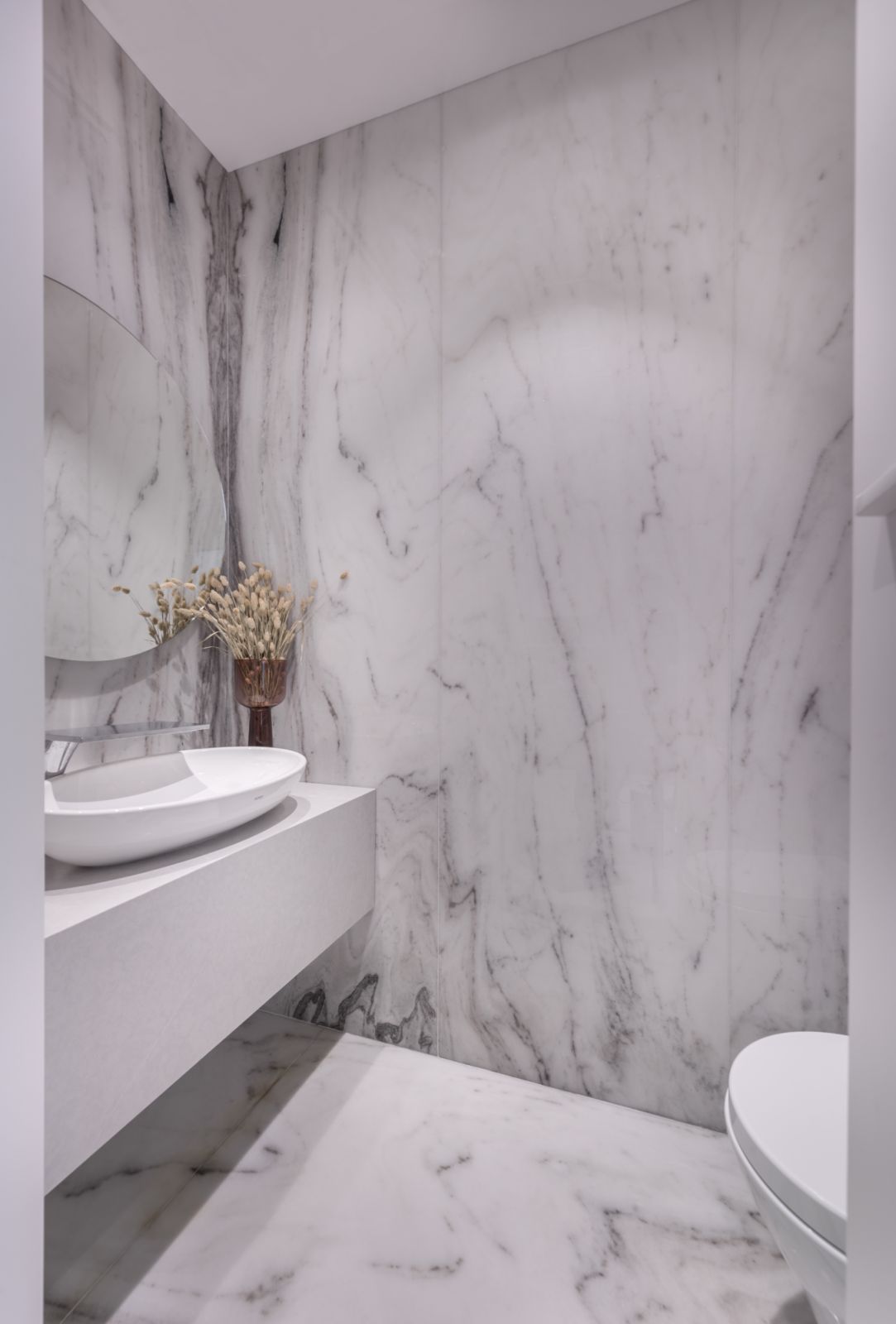 The classy powder room was wrapped in large-format marble tiles