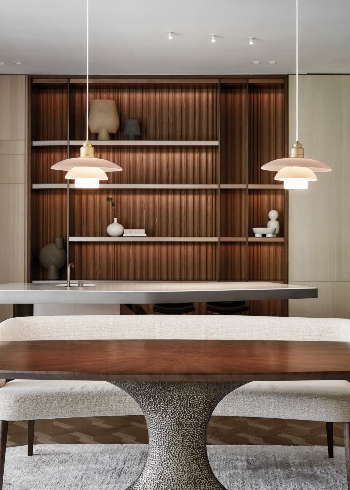 A pair of blush-toned Louis Poulsen pendant lights lends softness to the Meyer House dining area