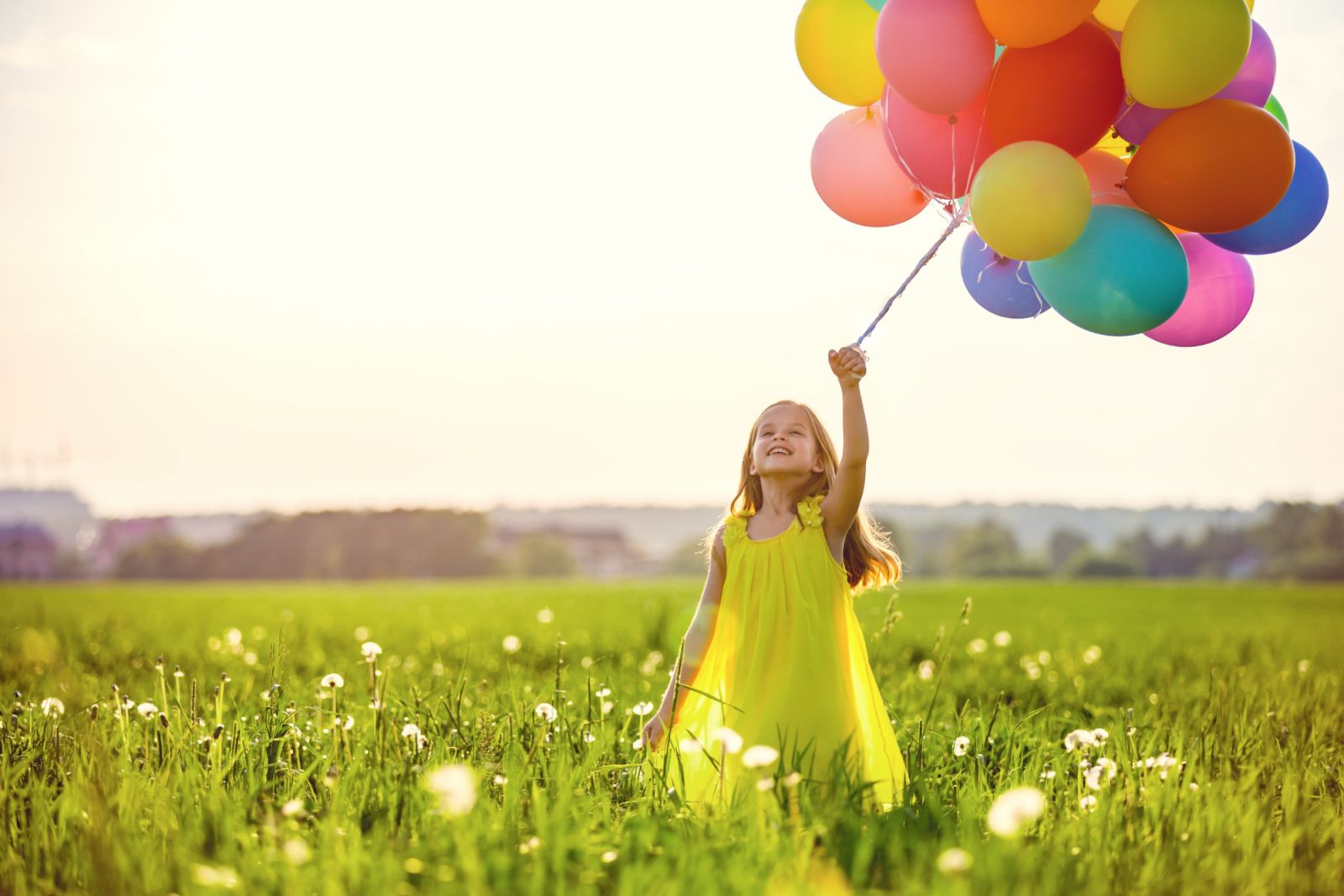 Little girl with balloons in the field