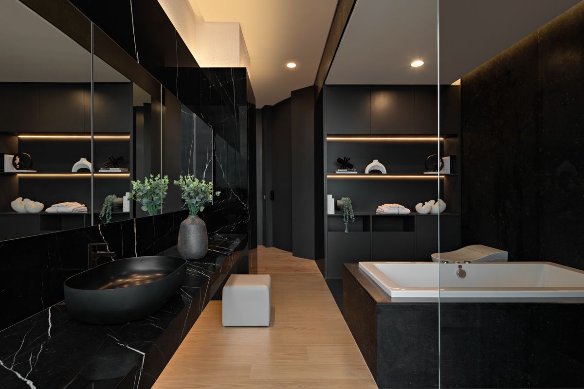 The master bathroom features dark walls that highlight the display shelves